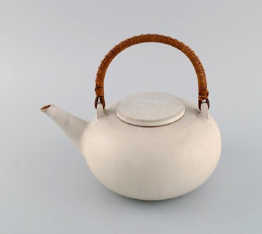 Eva Stæhr-Nielsen for Saxbo. Teapot in glazed stoneware with a wicker handle. 
Model number 50. Mid-20th century.
Measures: 23 x 18 cm (incl. handle).
In excellent condition.
Stamped.