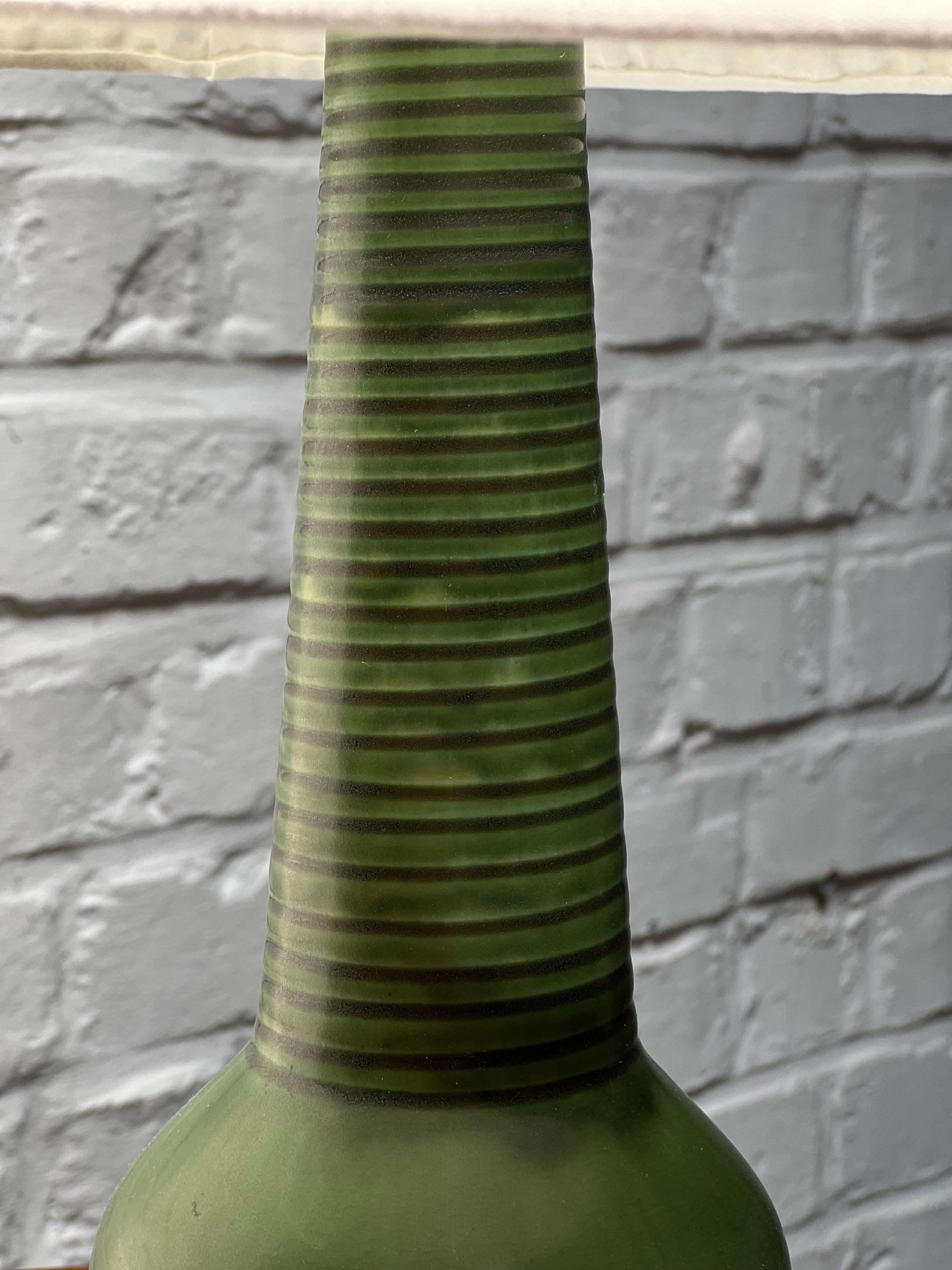 This is a very unique table lamp with a nice shade of green glaze. Its a higher piece than usual. This is a real lamp not a vase that was transformed later. You can see the glaze around the cable hole on the detail picture. A signature under the