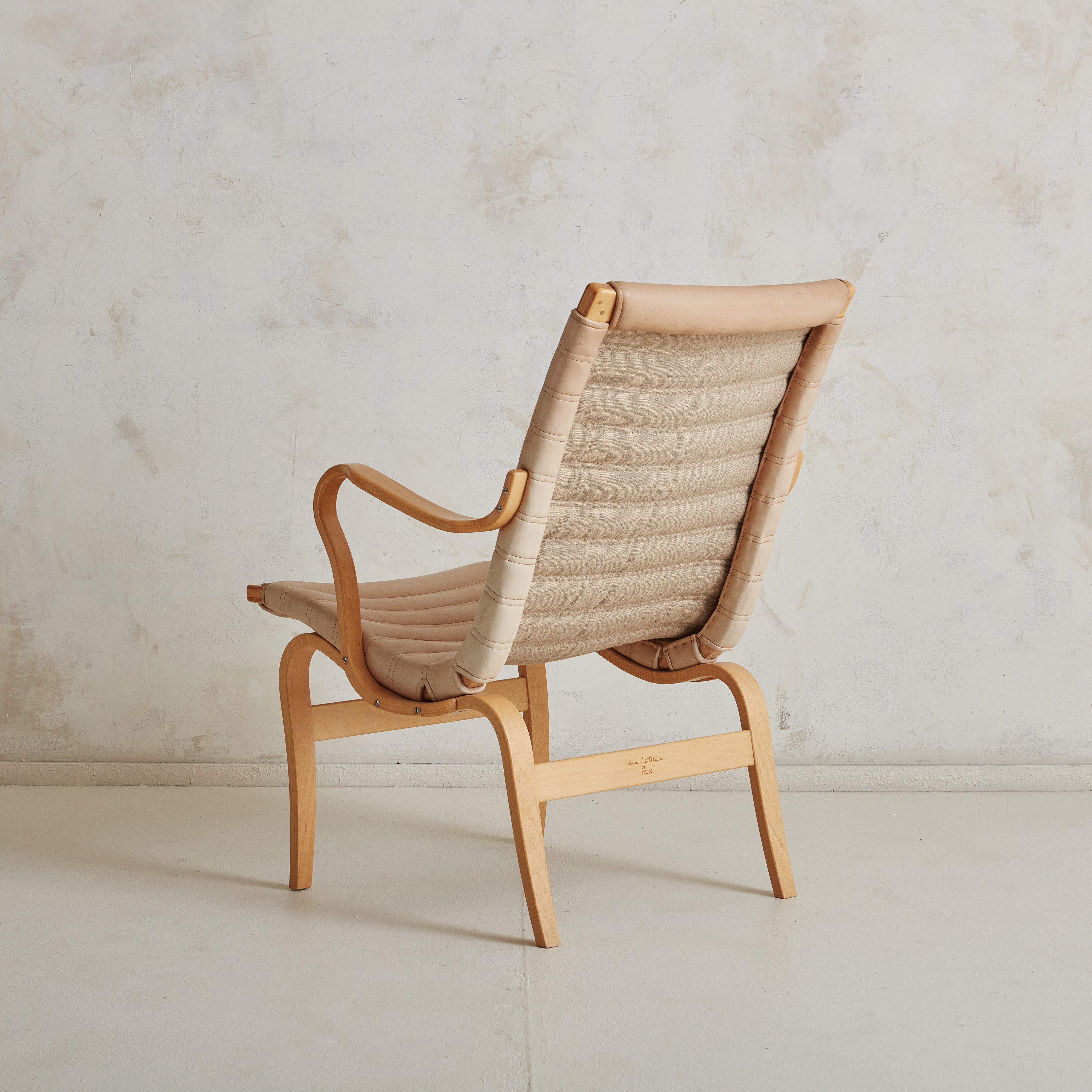 A 1960s Swedish ‘Eva’ lounge chair designed by Bruno Mathsson for DUX. This Scandinavian Modern lounge chair features a sculptural bent beechwood frame with dramatic curved arms and fluted legs. The creamy, off-white leather has natural aged patina