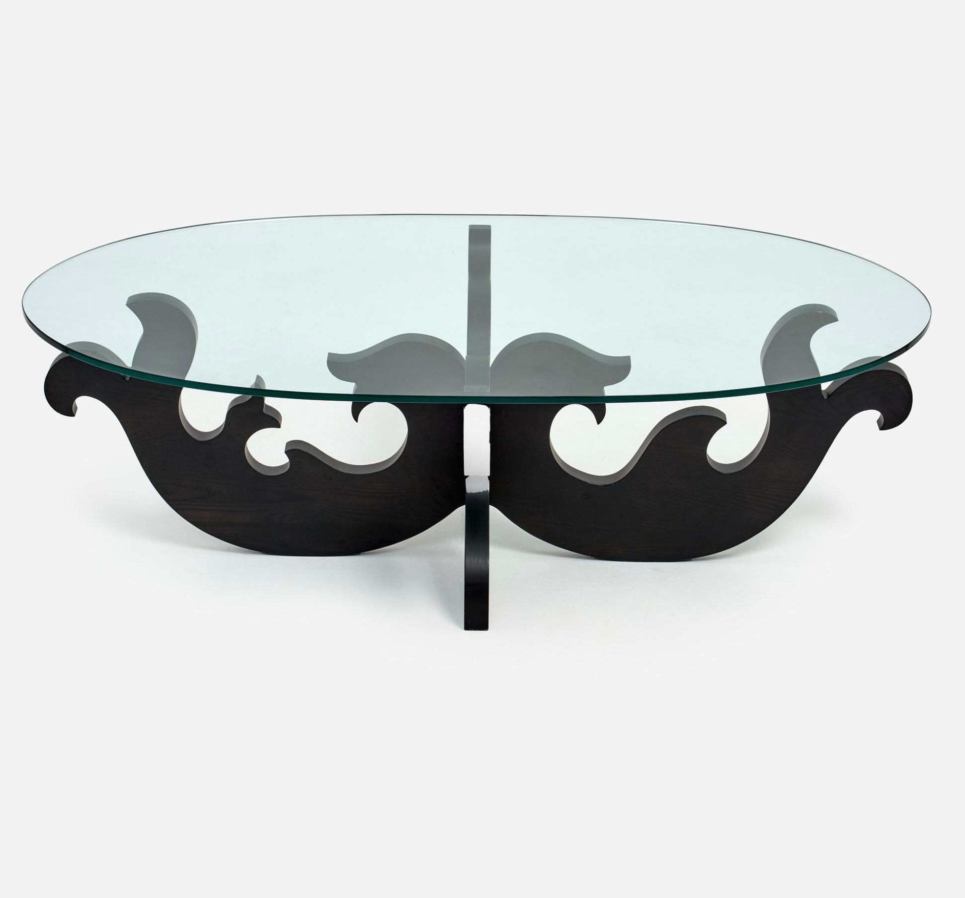 Une jolie table basse à plateau en verre conçue par Eva Zeisel pour Design Within Reach.  Le DWR a vendu ce produit au détail en 1993. Il n'est plus en production. La table a un plateau ovale qui mesure 58 pouces de long par 33 pouces de large. Il