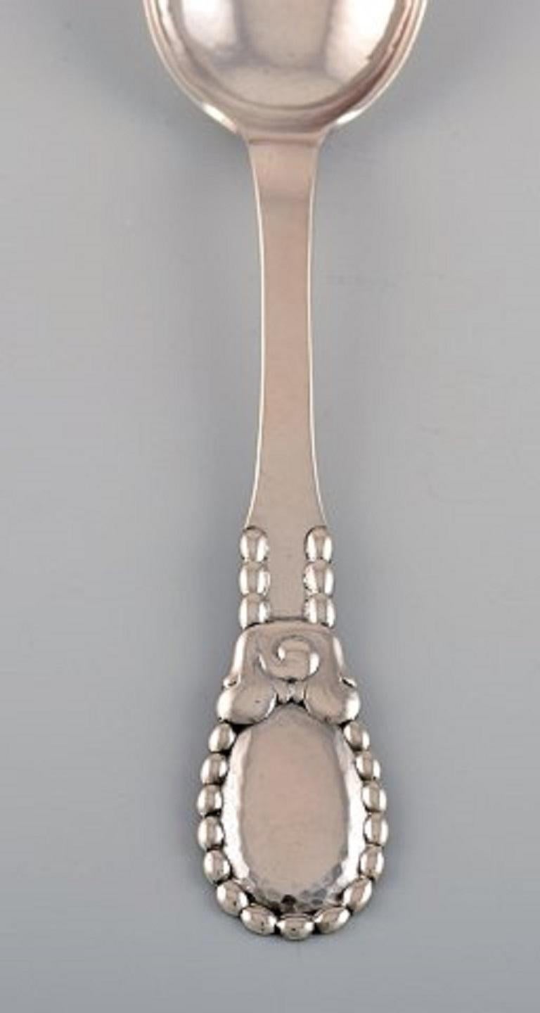 Evald Nielsen number 13 large tablespoon in hammered silver. 1920's. 
Six spoons are available.
Measure: Length: 21 cm.
Stamped.
In excellent condition.
Our skilled Georg Jensen silversmith / jeweler can polish all silver and gold so that it
