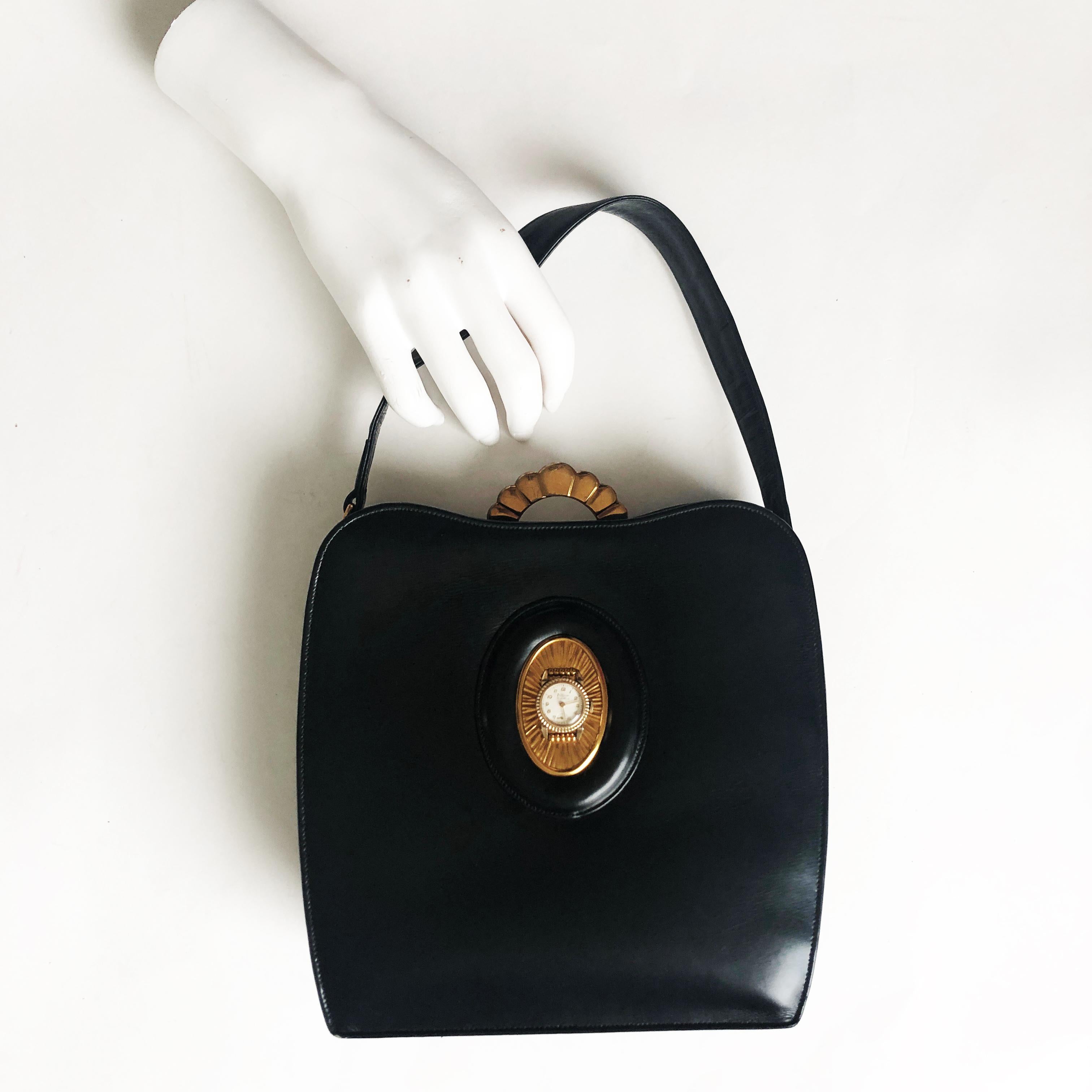 Authentic, preowned, vintage & RARE Evans Elegance black calfskin leather bag w/clock, circa 50s. Comes w/gold mirror compact & attached coin purse. Art Deco metal top closure, hinged, lined in satin w/slit pockets & 1 small open pocket.