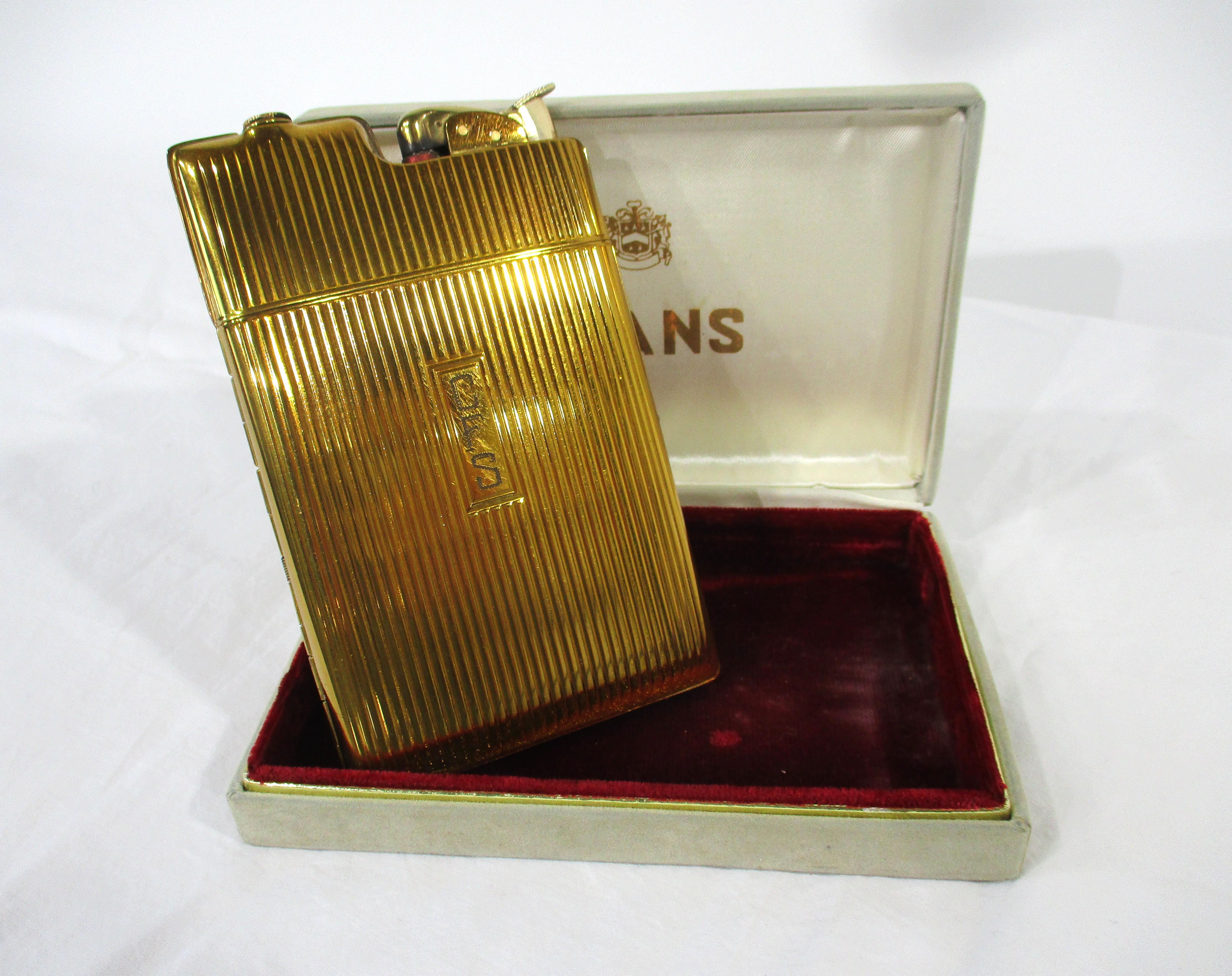 A gold toned flip open cigarette case with upper lighter, the inside having spring loaded wings to hold your cigs or other combustibles. Presented in its original manufactures display box made by Evans in the manner of the Alfred Dunhill company