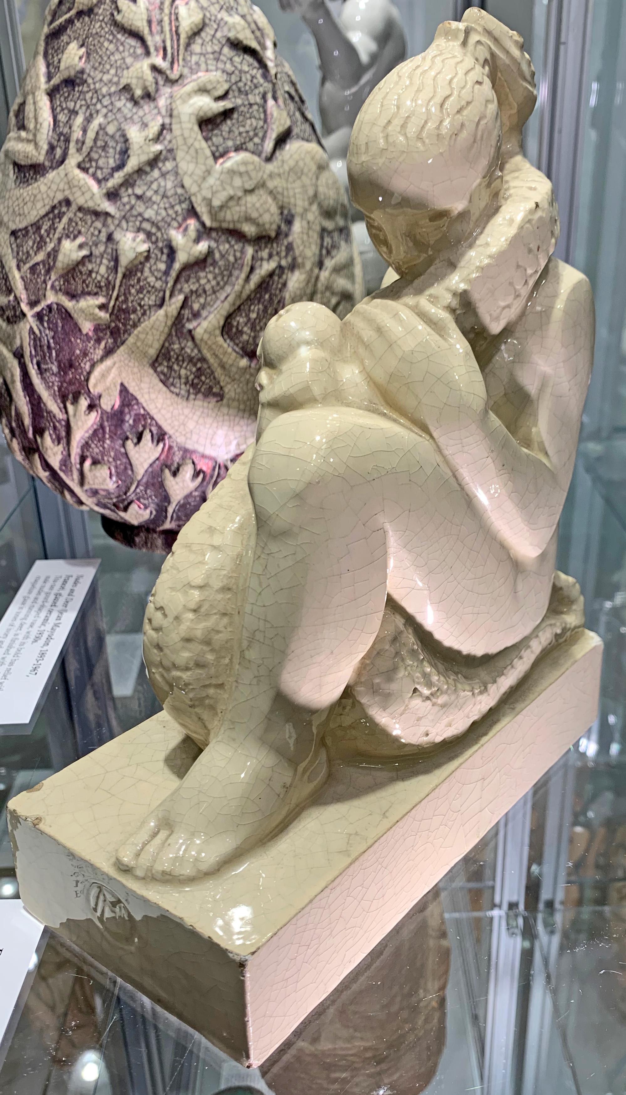 Superbly carved -- not molded -- and beautifully glazed, this stylized figure of Eve, sensuously encircled and surmounted by a powerful serpent, was sculpted by Marcel Merignargues, an important French artist who marked the piece with his 