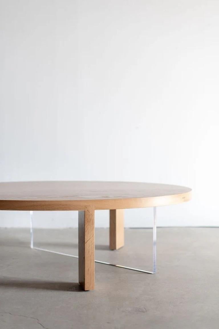 Der Couchtisch aus massiver Eiche hat eine ovale Platte, die von der Hirnholzmaserung zweier Beine asymmetrisch durchschnitten wird. Das natürliche Holz wird buchstäblich und ästhetisch durch eine transparente Lucite-Kufe ausgeglichen. Die Kufe aus