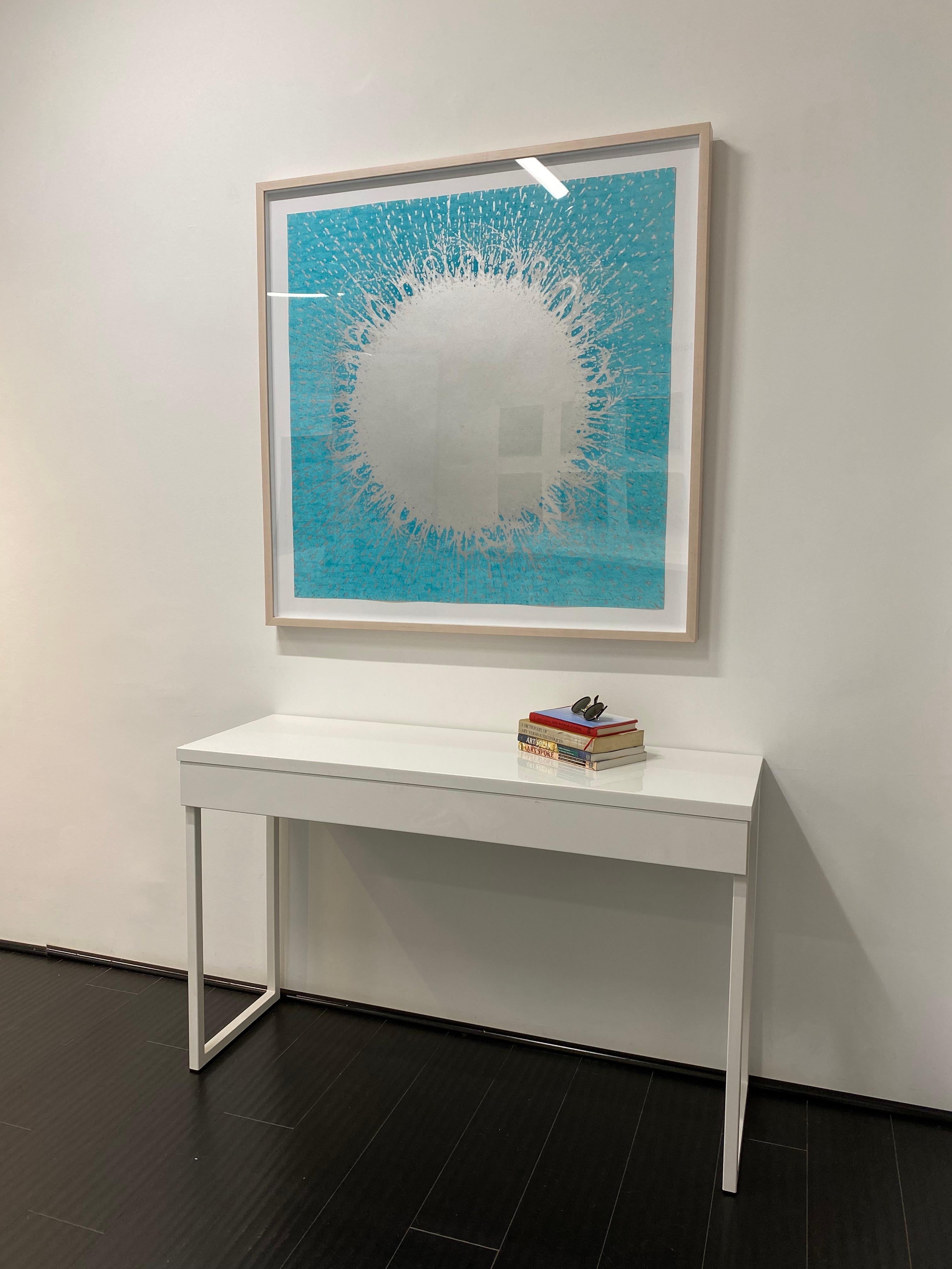 This square woodcut print on paper is composed of a central, circular, metallic silver shape spreading outward into an abstract pattern over a bright turquoise blue background that contrasts that subtle metallic sheen of the silver ink. The monotype