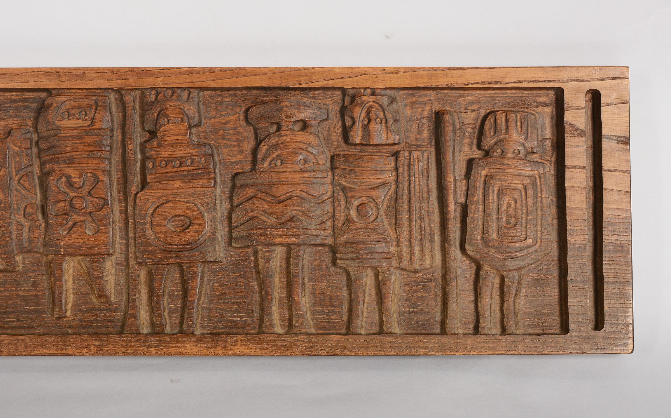 Large carved panel of tribal warriors designed by Evelyn Ackerman. The figures have very stylized and whimsical shields and headdress. The back is marked Era Industries and has a model number on it. The wood looks to be stained ash oak.