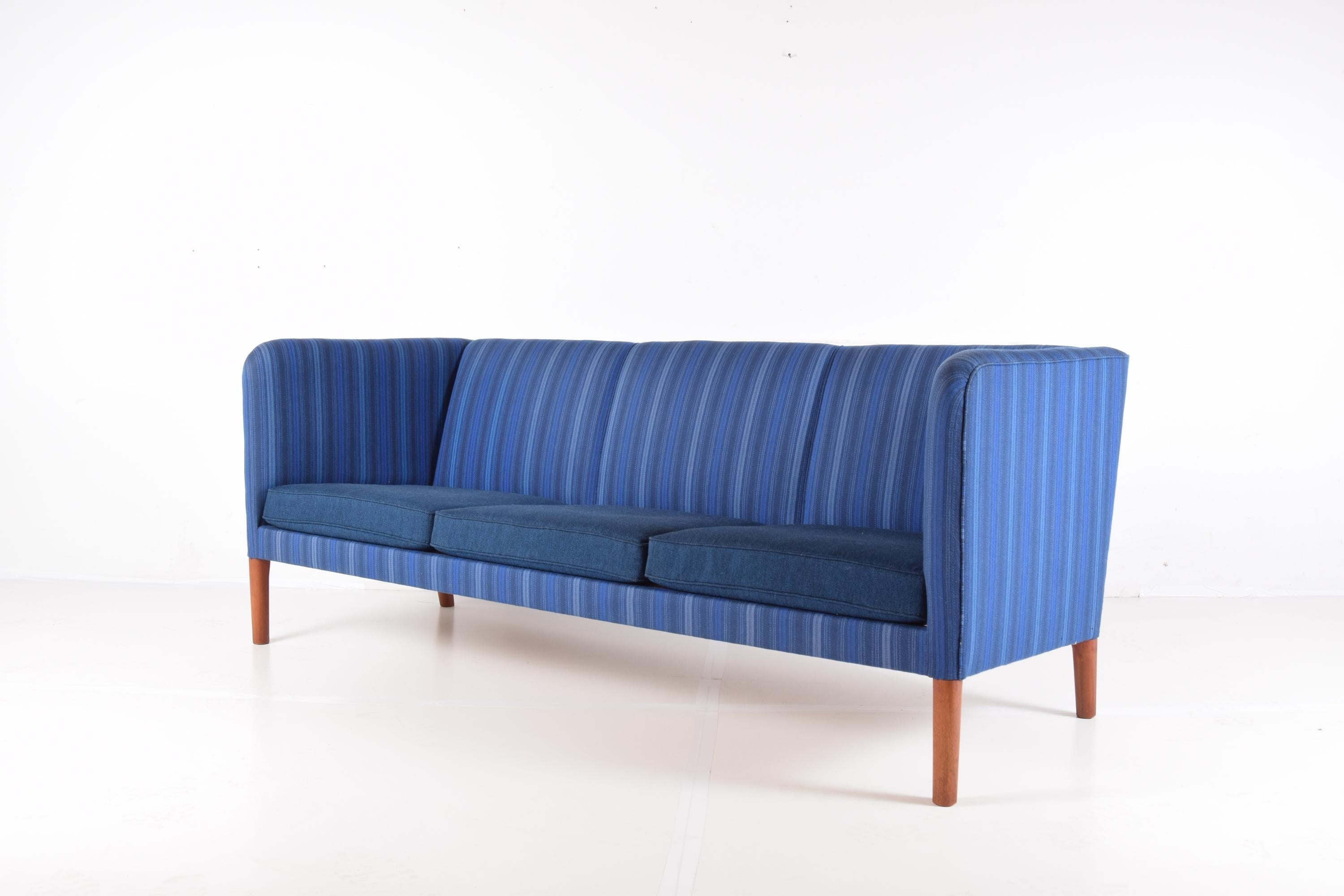 Elegant even arm sofa on tapered teak legs, designed by Hans J. Wegner, circa 1955. This example, produced by the workshop of A.P. Stolen, Denmark, circa 1971. Purchased from original owner who imported it from Copenhagen in 1971. Upholstered in the