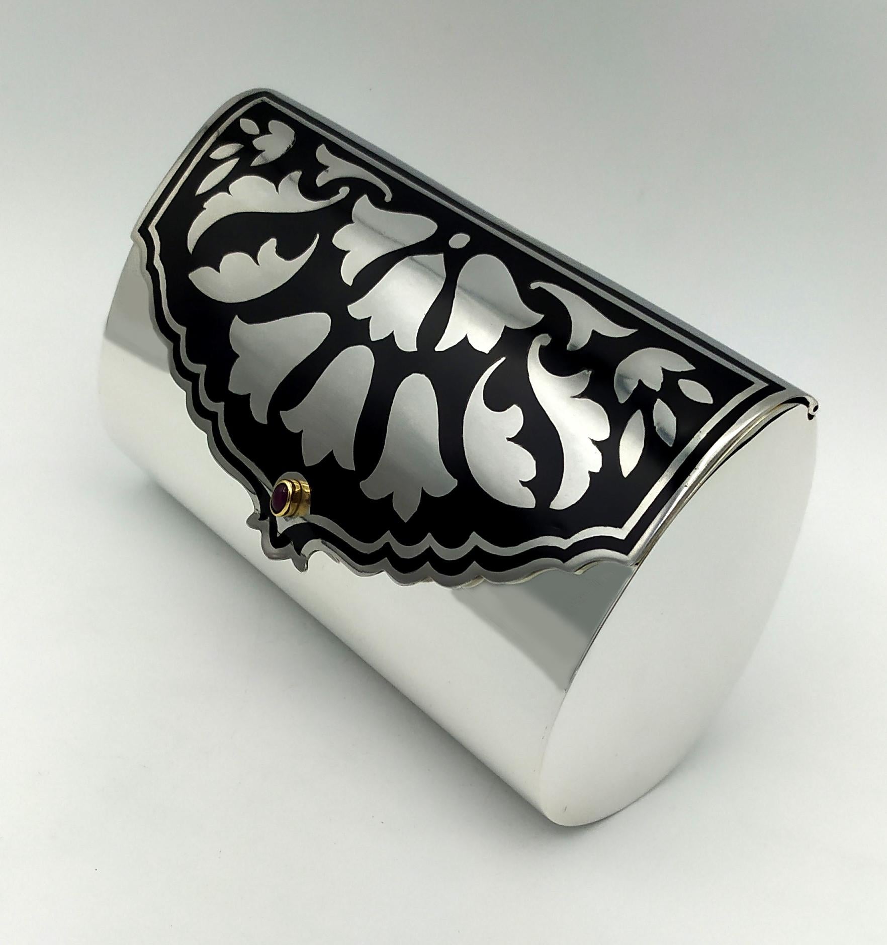 Bolso de noche ovalado de plata de ley 925/1000 con estilizados motivos florales esmaltados en estilo Art Déco. Tomado de un dibujo original de Louis Cartier de principios del siglo XX a partir del cual se elaboró el bolso donado a Mary Pickford, y