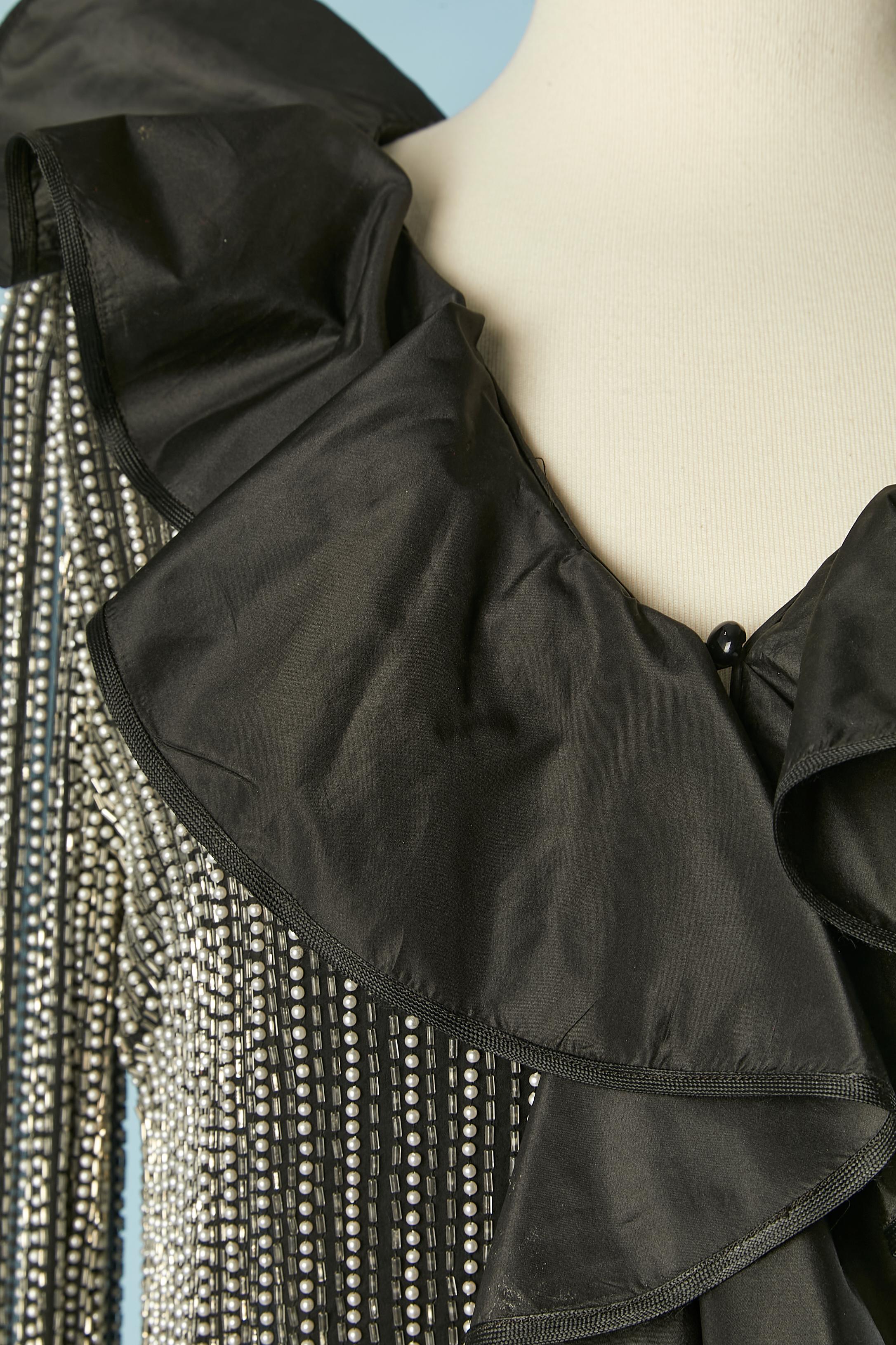 Chemise de soirée en mousseline de soie perlée et bordée de volants en taffetas noir. Bouton et boutonnière au milieu du devant.
TAILLE M