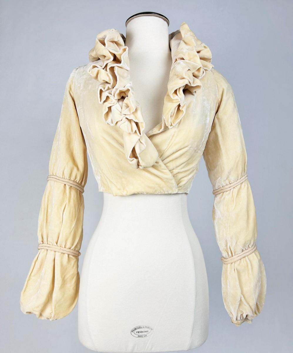 Circa 1930

France

Iridescent velvet panne evening bolero in eggshell cream dating from the 1930s, designed by Paule Haute Couture in Lyon. Fitted and crossed at the front in a wrap-around style, with a large V-neck in matching velvet.