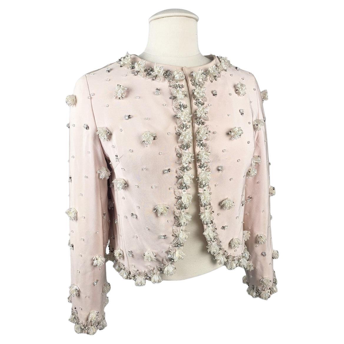 Circa 1965
France
Evening bolero in powder pink silk crepe by Marc Bohan for Christian Dior, numbered 23343 and dating from the 1960s. Straight cut, crew neck and long sleeves, fully embroidered around the edges. Rich embroidery, probably by