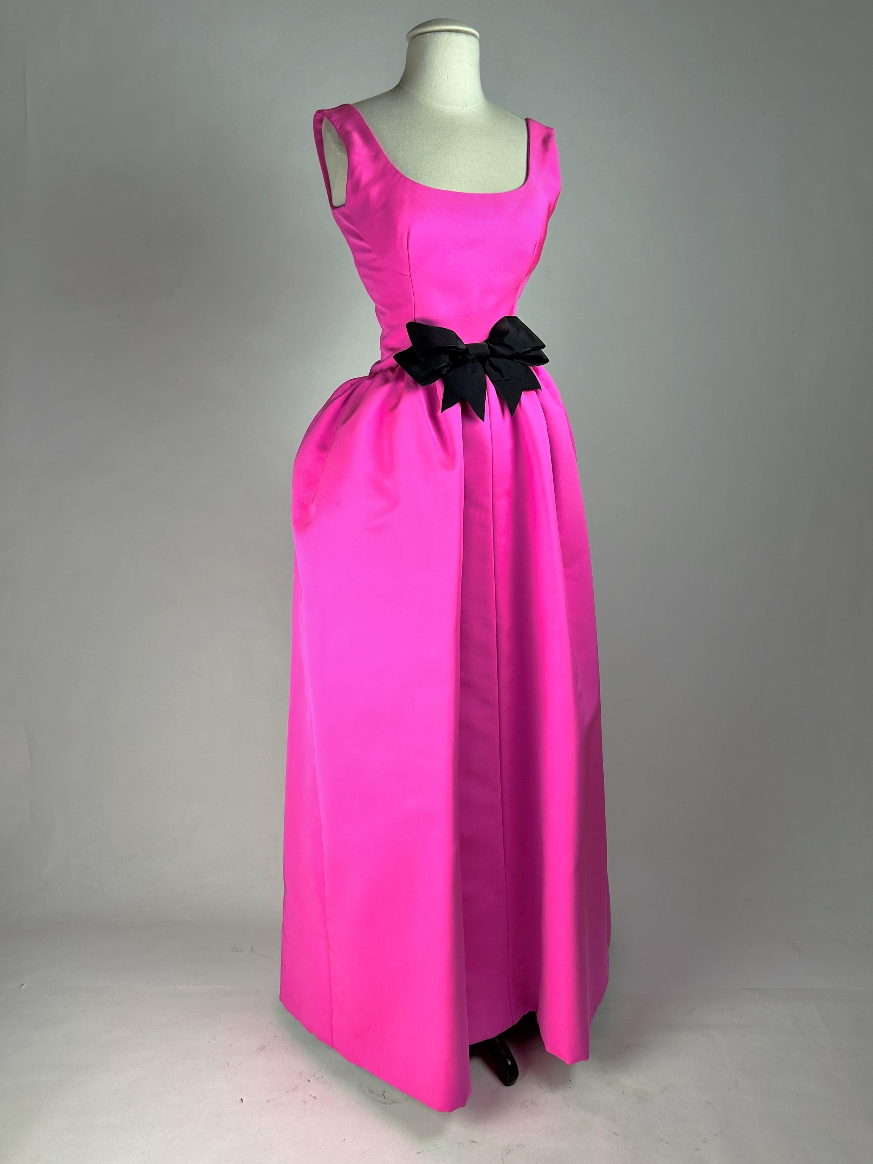 Circa 1962-1965

Paris

Evening dress by Cristobal Balenciaga, Haute Couture (attributed to) in Gazar Magenta dating from the early 1960s. Long dress with curved bustier, sleeveless and oval neckline. Tipped waistline highlighted by a large black