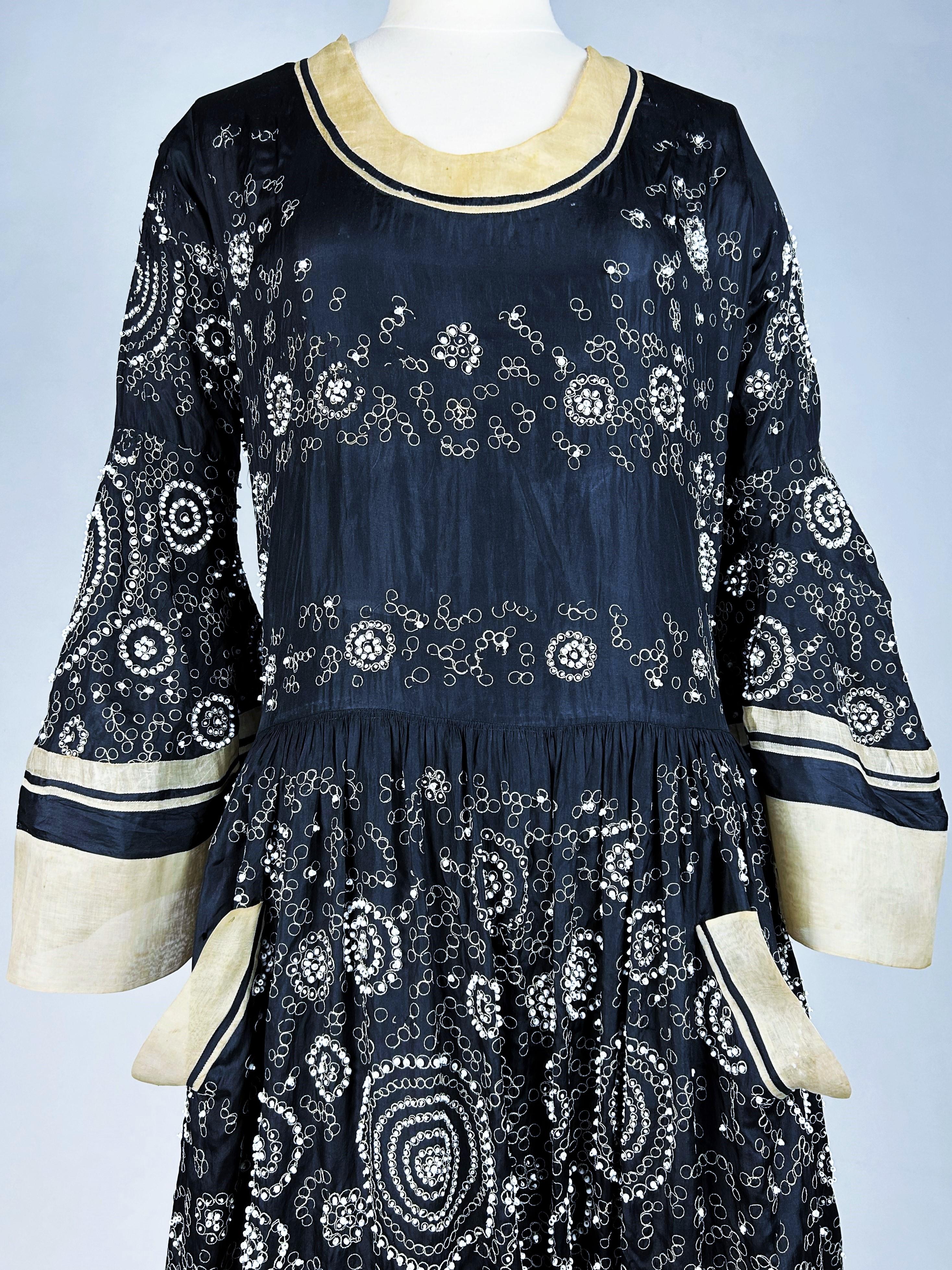 Verano de 1924

París

Vestido de noche de tafetán bordado negro y crema de Jeanne Lanvin Alta Costura de la colección de 1924. Inspirado en los Ballets Rusos, este icónico vestido de escote redondo, largas mangas pagoda y bajo de falda plisado en