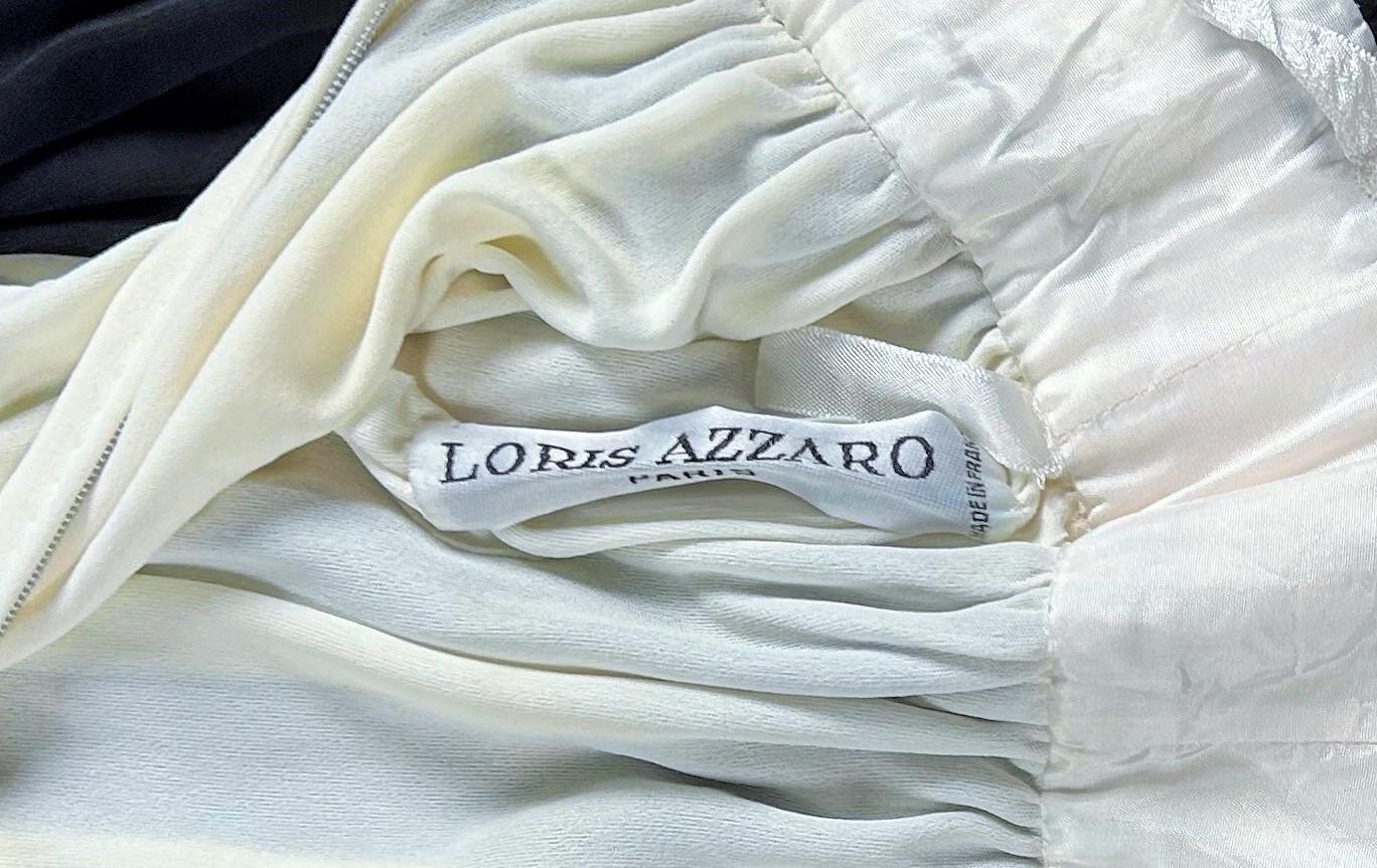 CIRCA 1980
Frankreich
Langes Abendkleid aus schwarzem und weißem Seidenjersey von Loris Azzaro Couture aus den 1980er Jahren. Ärmelloses Schößchenkleid mit tiefem V-Ausschnitt am Rücken und Reißverschluss. Der weiße Rock spielt mit zwei Farben und