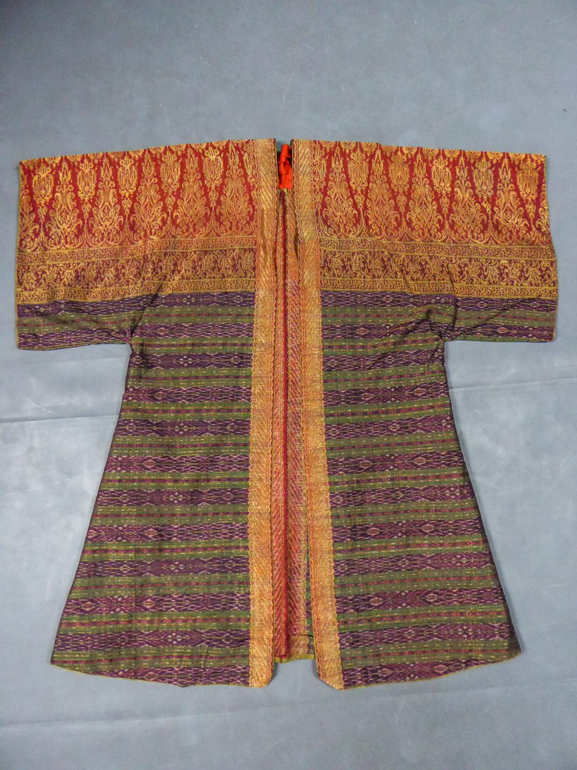 Circa 1960
France
Kaftan kimono evening jacket in red, green, purple and gold silk brocade from the 1960s. Former Indonesian or Thai ceremony shawl turned into kaftan without being cut. Kaftan cut with three quarter sleeves. Striped patterns in Ikat