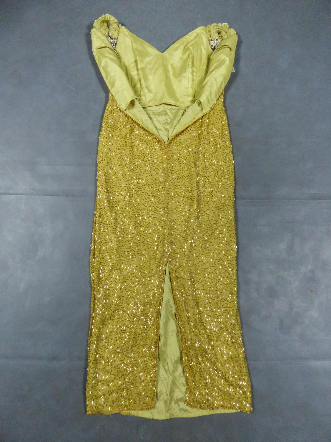 CIRCA 1980/1990
Frankreich

Wunderschönes langes Abend- oder Showkleid aus strohgelbem Seidenmusselin, vollständig bestickt mit goldenen Röhrenperlen und Zuchtperlen aus den 1990er Jahren. Bustier mit tiefem Rückenausschnitt, verziert mit Perlen und