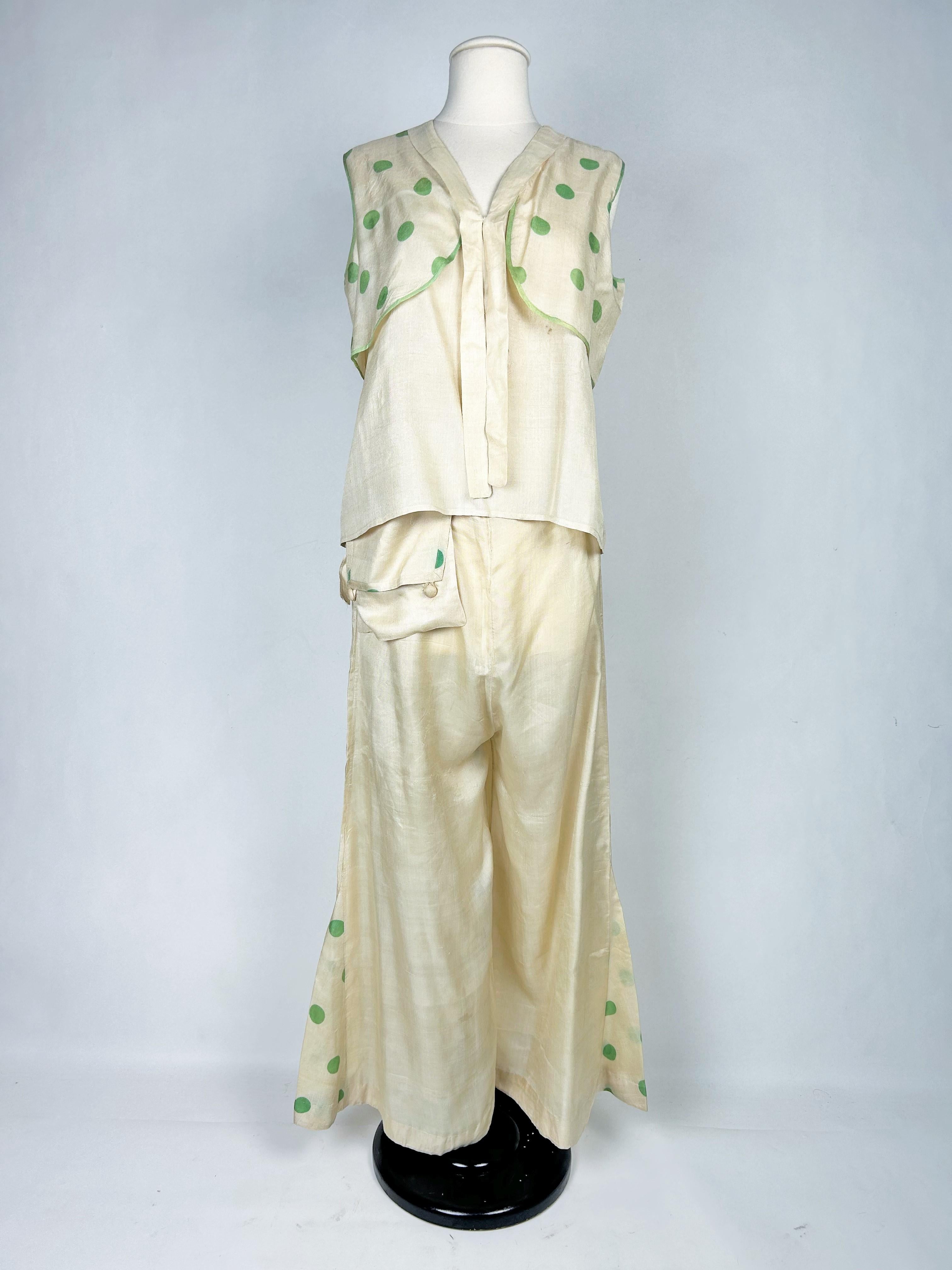 Circa 1930 France
Un joli pyjama de soirée, deux pièces, pantalon et corsage en pongé de soie crème imprimé de gros pois vert tendre, datant des années 1930. Pantalon taille haute à jambes évasées, poches et bas du pantalon faisant écho à l'imprimé