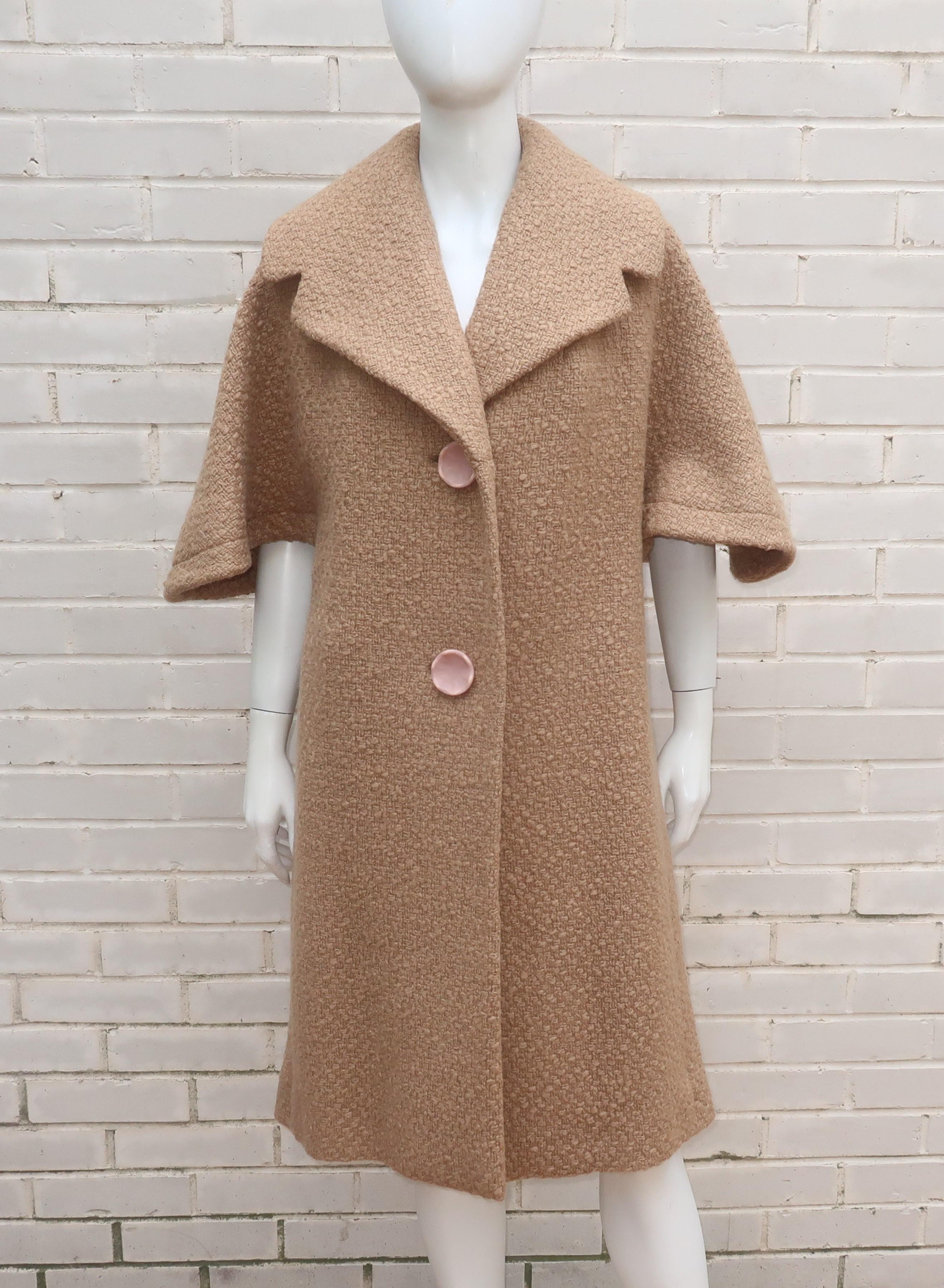 1950’s taupe wool boucle coat with unique 3/4 sleeves that provide a capelet style silhouette.  The coat buttons at the front and features faux vent panels at the sides with hidden pockets.  Fully lined in silk satin.  It has a Hitchcock heroine