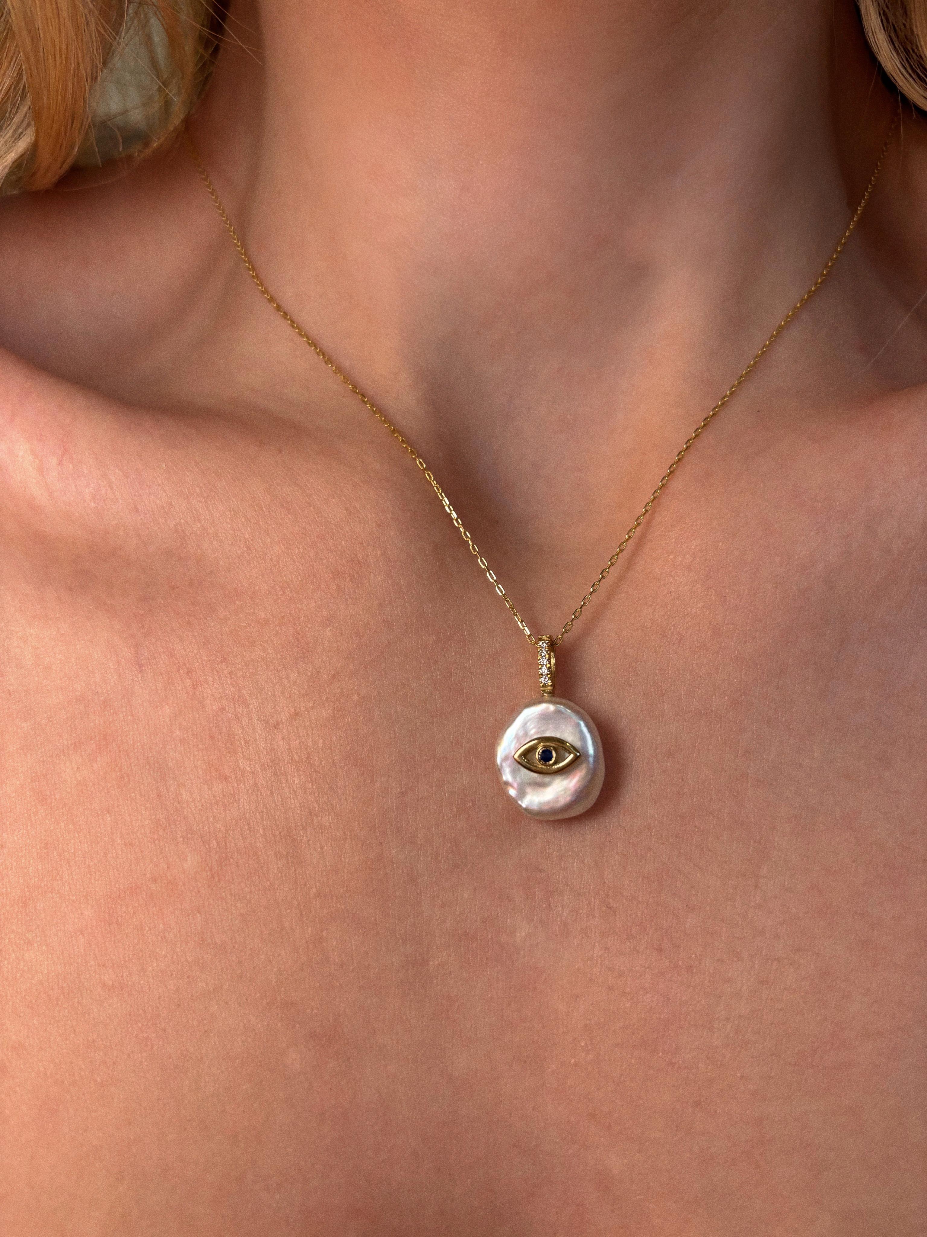 Unsere 'Evil Eye Pearl Necklace' ist aus 18 Karat Gelbgold gegossen und mit einem natürlichen Saphir und natürlich schimmernden Diamanten auf einer blütenförmigen Süßwasserperle besetzt. Er soll seinen Träger schützen und jegliche negative Energie