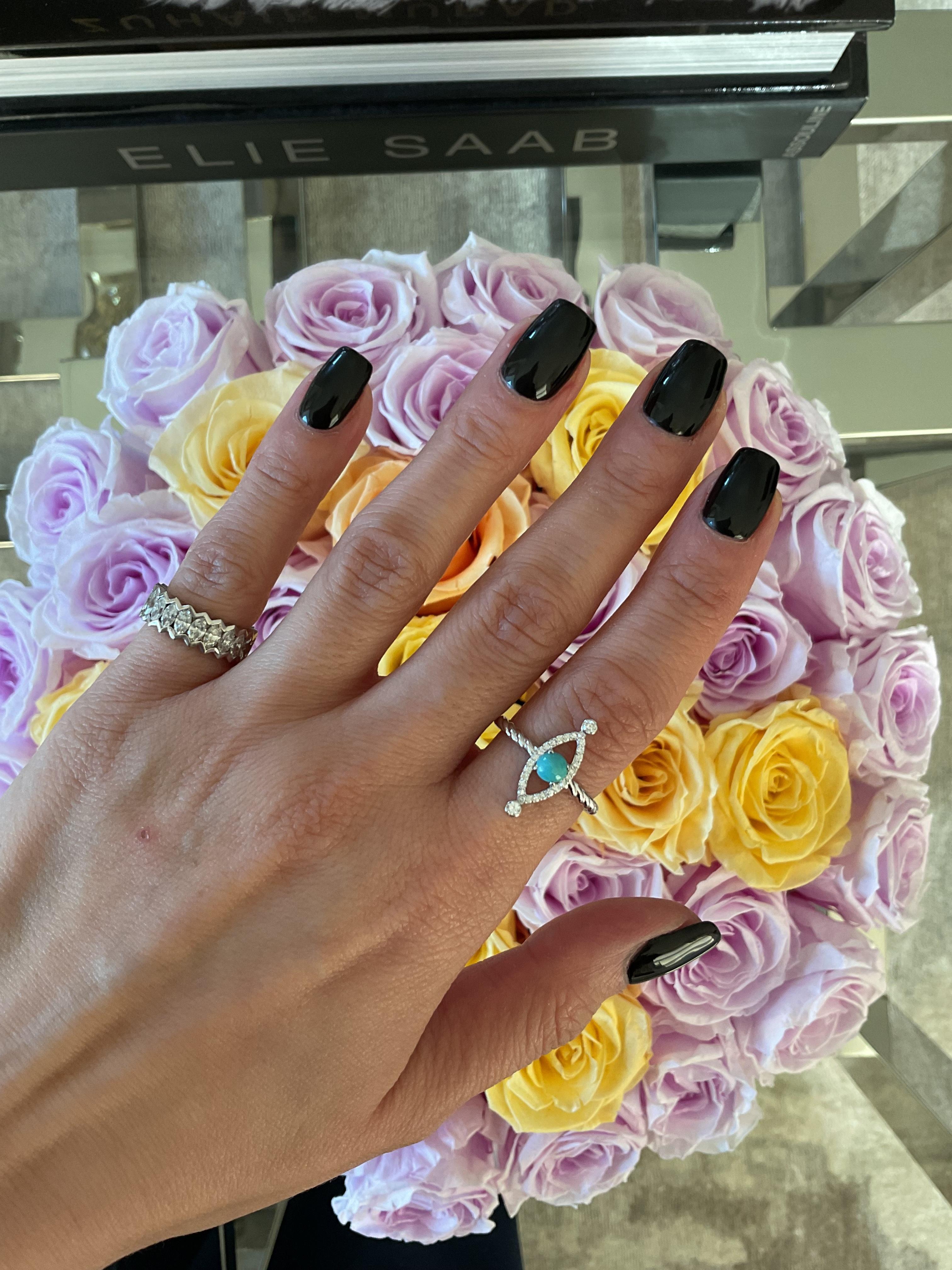 Elaborado en oro blanco de 18 quilates, el Anillo Ojo de Mal de Linea presenta un diseño de banda retorcida que combina la elegancia moderna con la protección simbólica. Su piedra central redonda de turquesa está delicadamente enmarcada por un borde