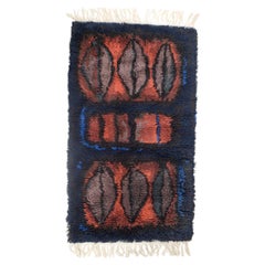Evy Viola Wiklund. Hand-knotted rya carpet in warm red, black, and blue tones.