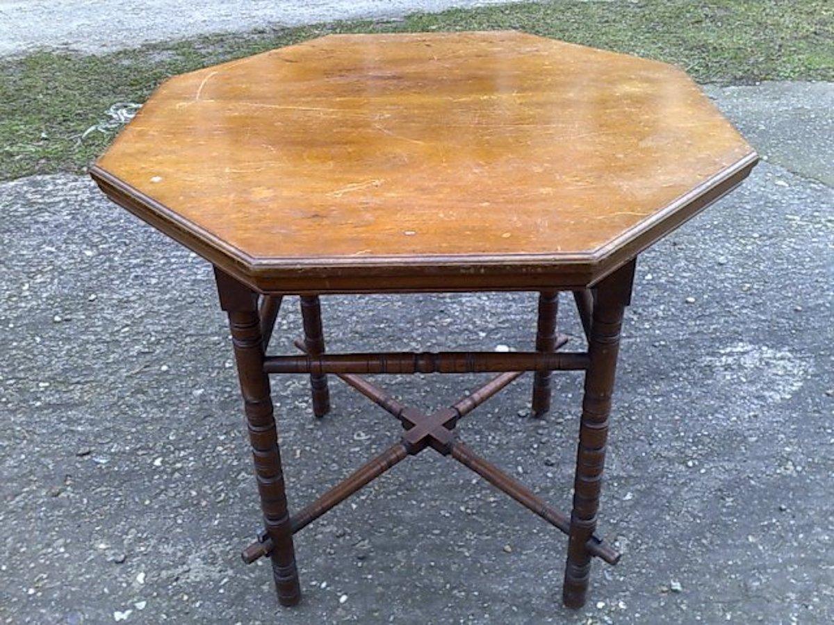 E.W. Godwin in the style of. 
An Aesthetic Movement Walnut octagonal centre or side table with arched apron below the top, he legs united by upper stretchers and also united by a lower a cross stretcher which follows through the lower legs with
