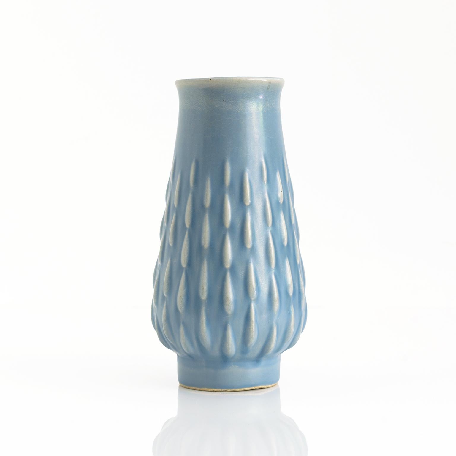 Vase mit Fuß von Ewald Dahlskog, glasiert, blassblau, mit erhabenem Muster. Signiert auf der Unterseite ED mit Herstellermarke für Bo Fajans. In Schweden hergestellt, ca. Ende der 1930er Jahre. 

Maße: Höhe: 8, Durchmesser: 4,25.