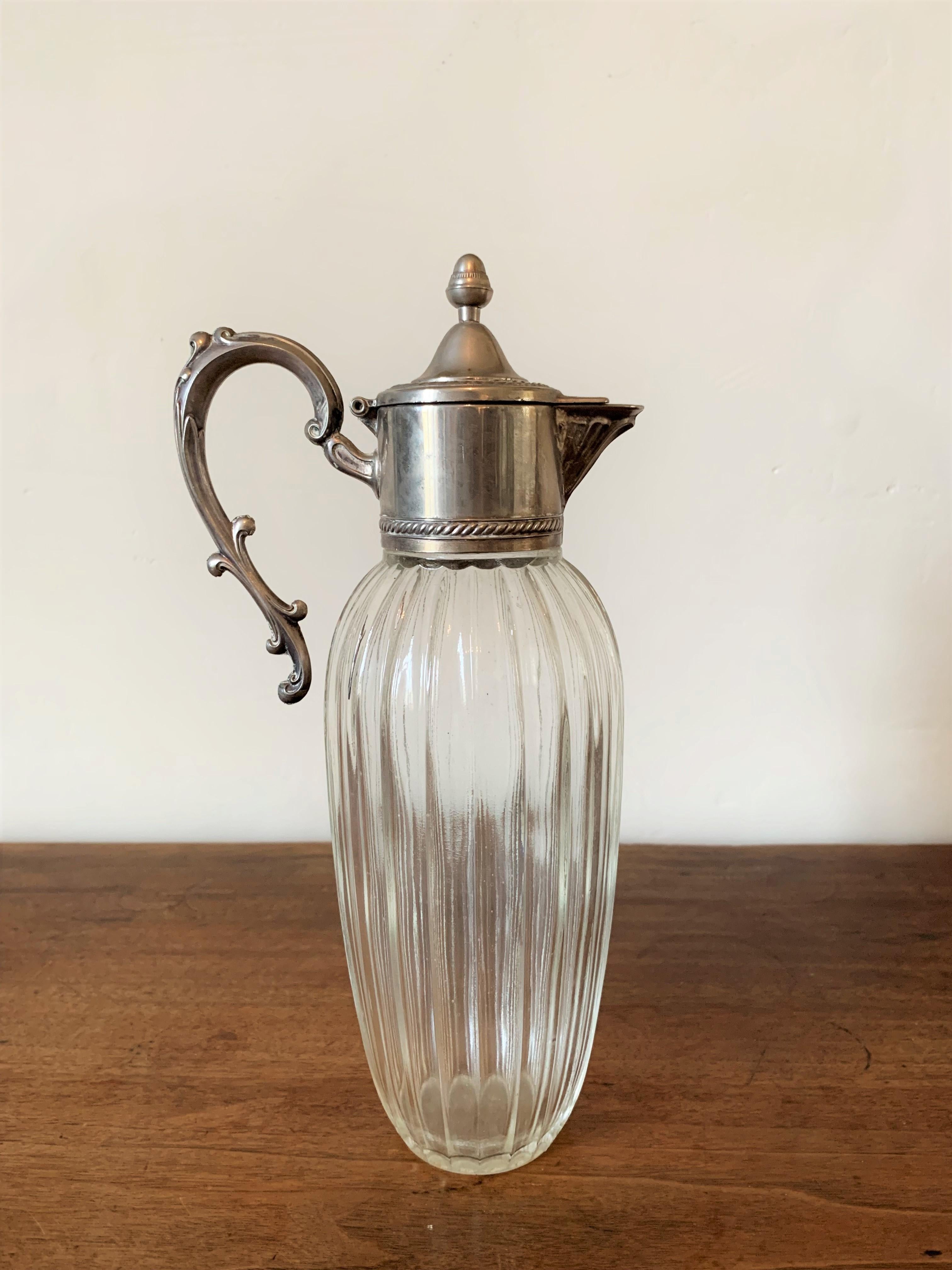 Very nice ewer, carafe from the early 20th century. The body is made of chased glass while the handle and spout are made of pewter, a very rare element and one of the oldest known at least since antiquity. The handle is graceful with a vegetal