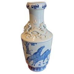 Grand vase chinois entouré de dragons bleus et blancs entourant des chevaux