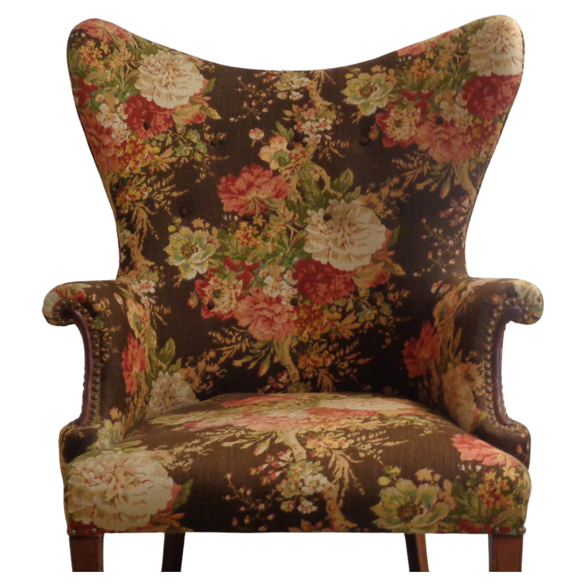  Exaggerated butterfly back wing chair w/ tapered mahogany legs / brass tacking at wood accented rolled arms & top of front legs / original floral design cotton linen upholstery w/ button decorated front backrest. Beautiful chair. Circa 1940. Look