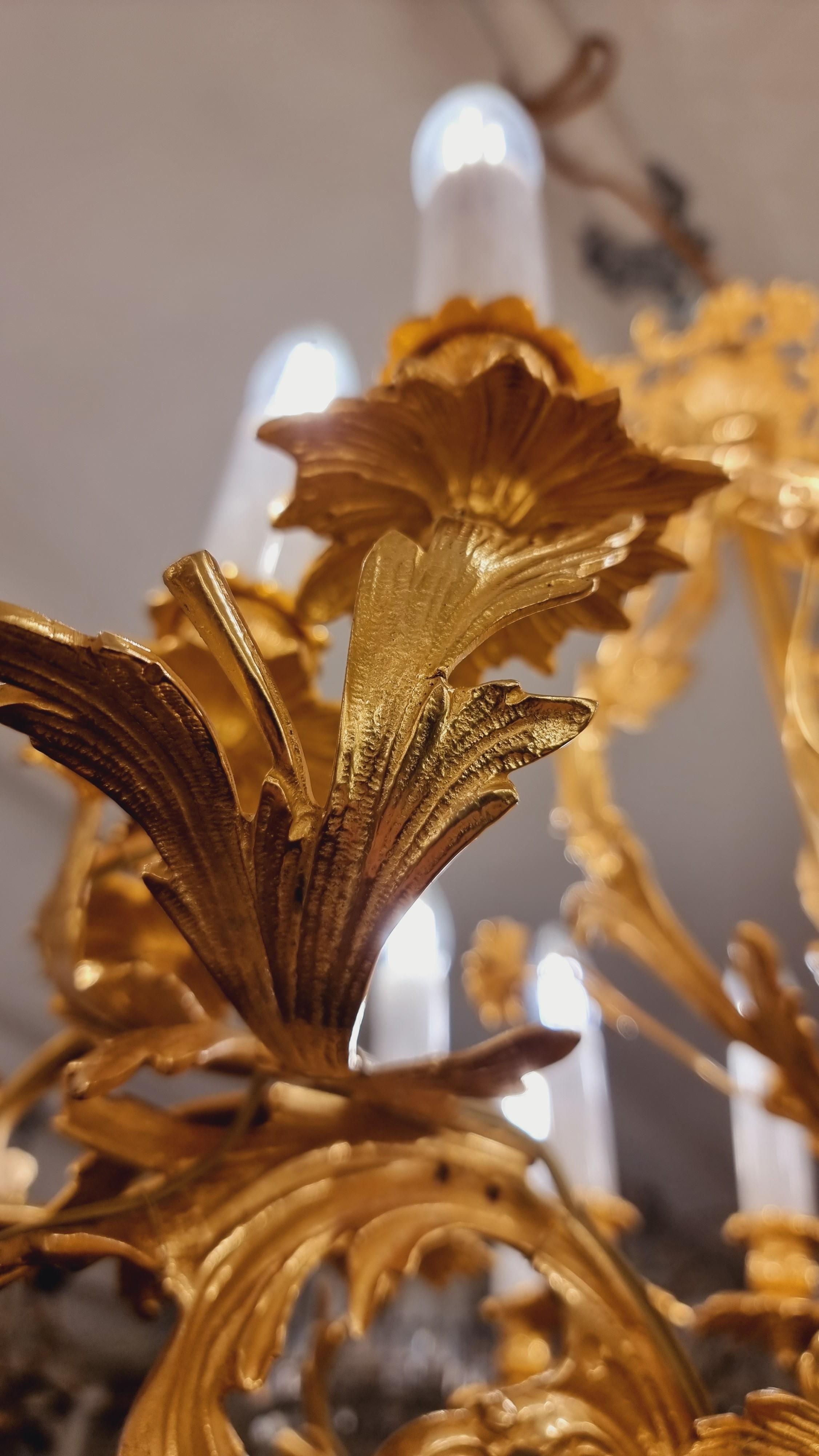 Ein prächtiger bronzevergoldeter französischer Rokoko-Kronleuchter mit goldenen Blättern und 4  Flachreliefs. Mit 16 Flammen an vier Armen. Komplett neu verkabelt für EU-Standard (wir können kostenlos auf US-Standard umstellen). my instagram