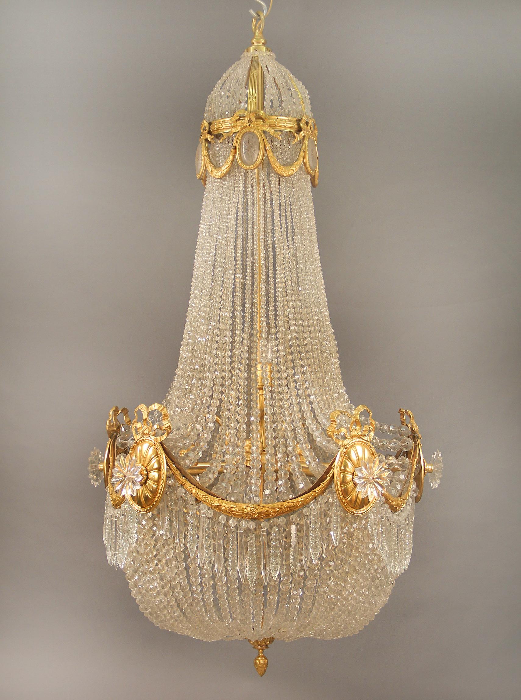 Ein hervorragender Kronleuchter mit fünf Lichtern aus vergoldeter Bronze des späten 19. und frühen 20.

Die feine Perlenkrone ist mit bronzenen Schwänzen und Schleifen gestaltet, in deren Mitte sich Medaillons in geätztem, mattiertem Kristall