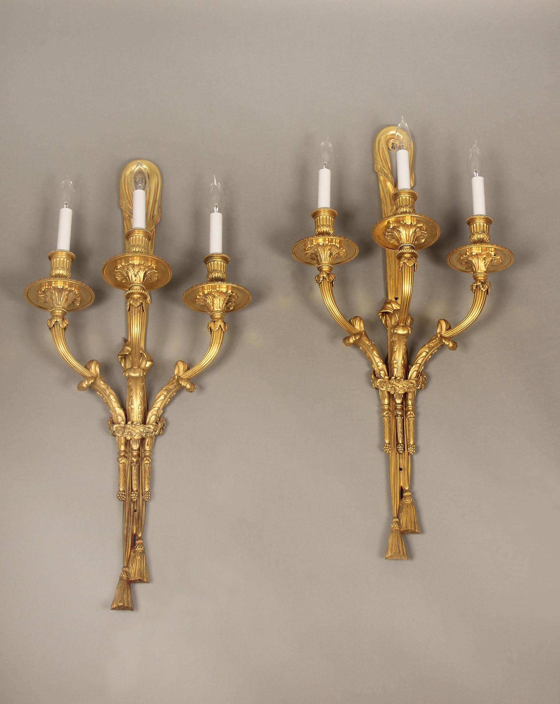 An excellent pair of early 20th century gilt bronze three-light sconces.

By Caldwell

A ribbon back above a body and three arms with floral and foliage designs.

Stamped C on the back of each sconce.

Edward F. Caldwell & Co., of New York