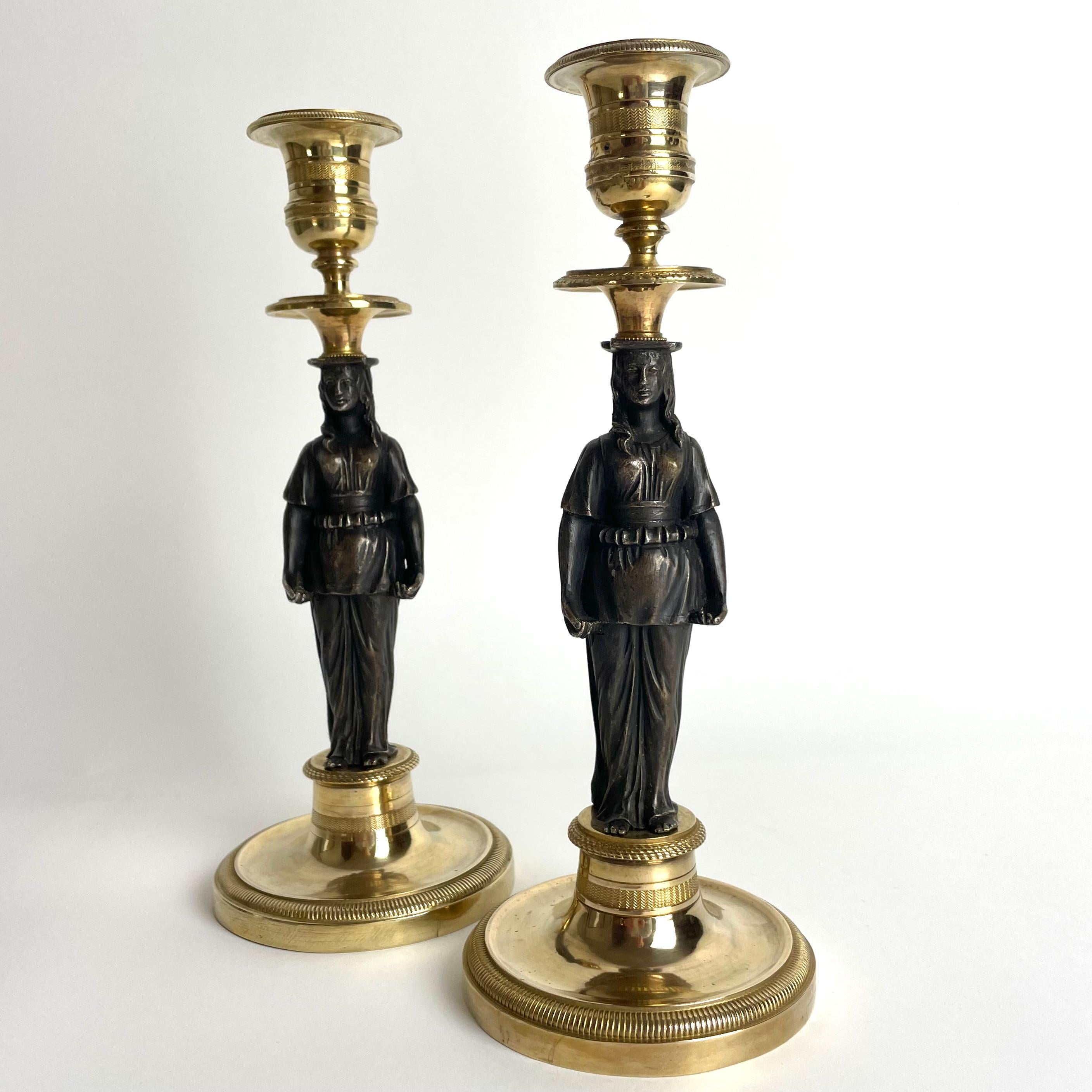 A beautiful pair of gilded candlesticks with dark patinated caryatids in bronze. French empire, circa 1820.

Wear consistent with age and use.