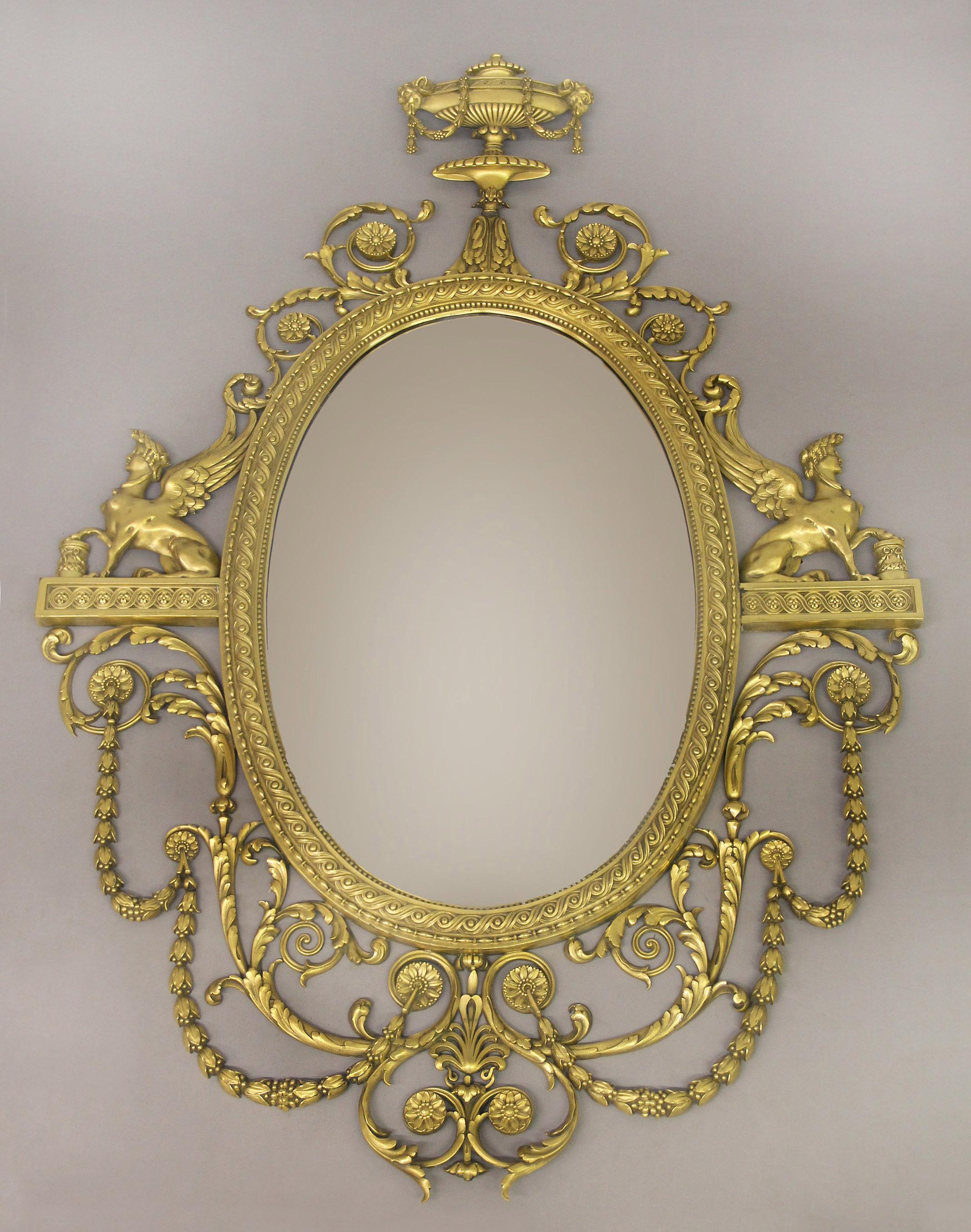 An excellent quality early 20th century gilt bronze mirror by Caldwell

Edward F. Caldwell and Co. Inc. New York

The oval mirror within a guilloche and beaded frame, surmounted by an urn with rams heads draped with husk-festoons and above