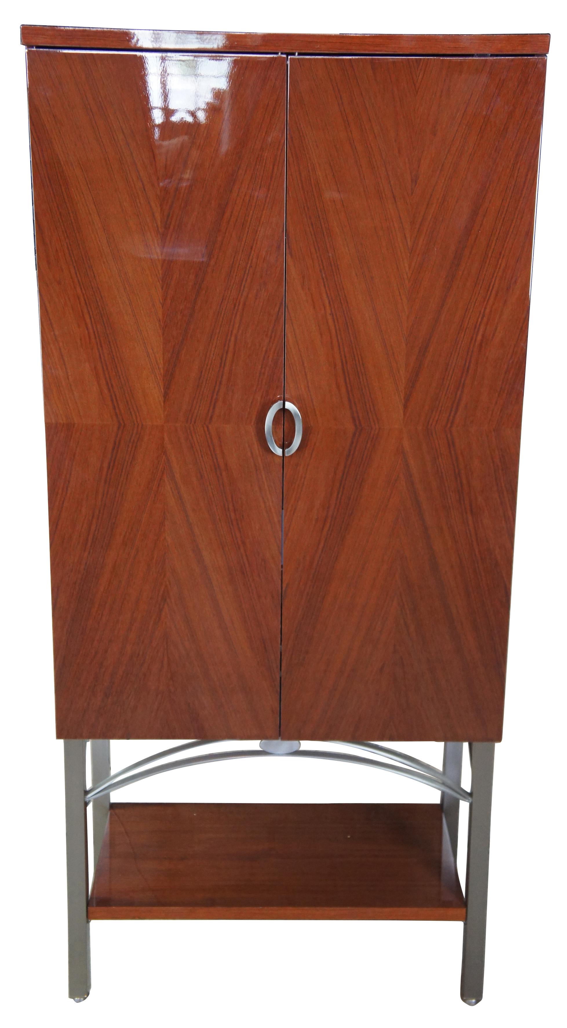 Excelsior designs contemporary lacquered rosewood and steel dry bar, circa 1990. Features matchbook veneered door panels that open to illuminate two interior glass shelves, pull out tray, bottle storage and two drawers. Measures: 79