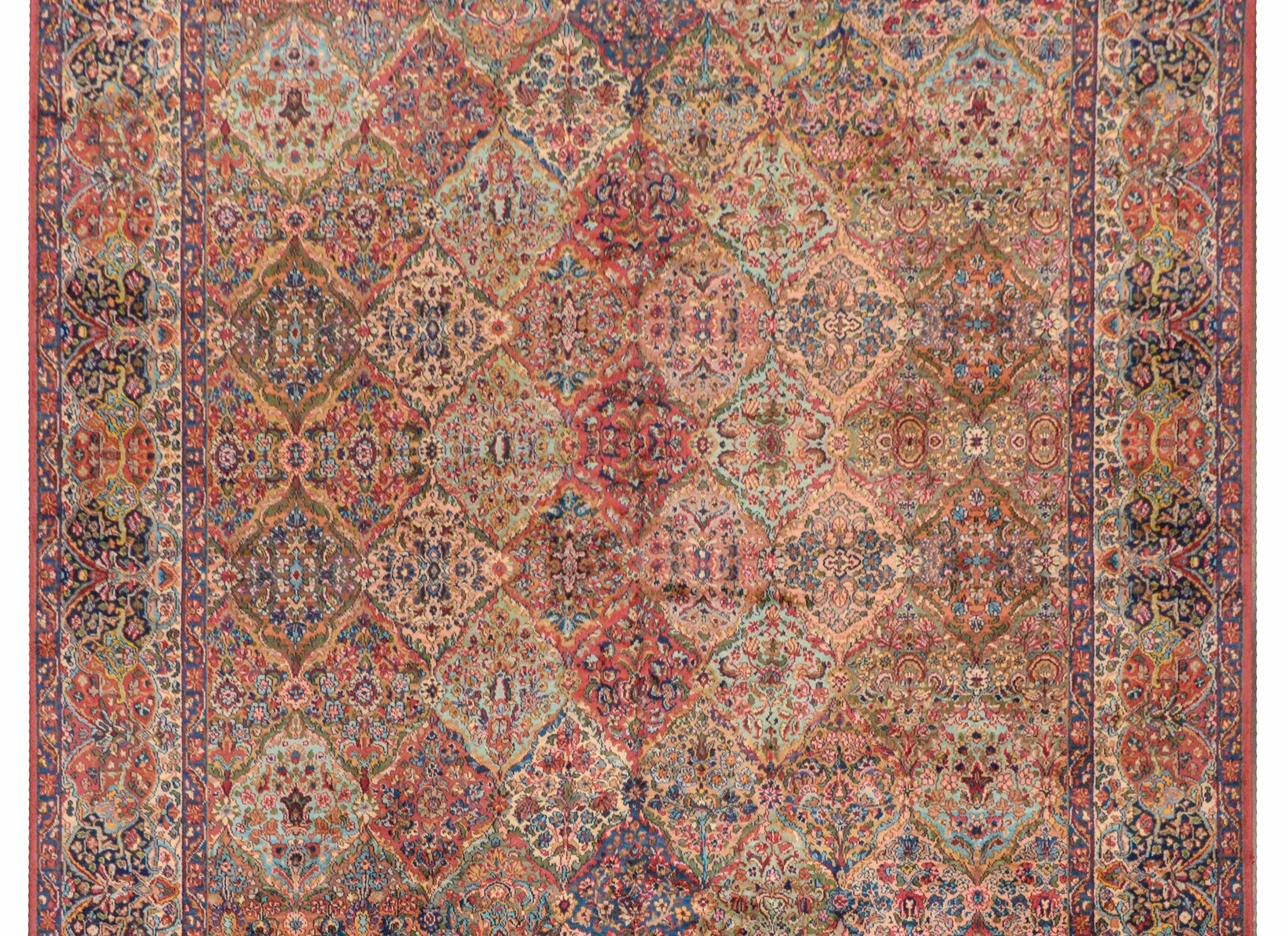 An exceptional early 20th century Persian Karastan Kirman rug with a beautiful all-over patchwork pattern containing myriad flowers woven in myriad colors across the field, and surrounded by a border of similar pattern and colors.