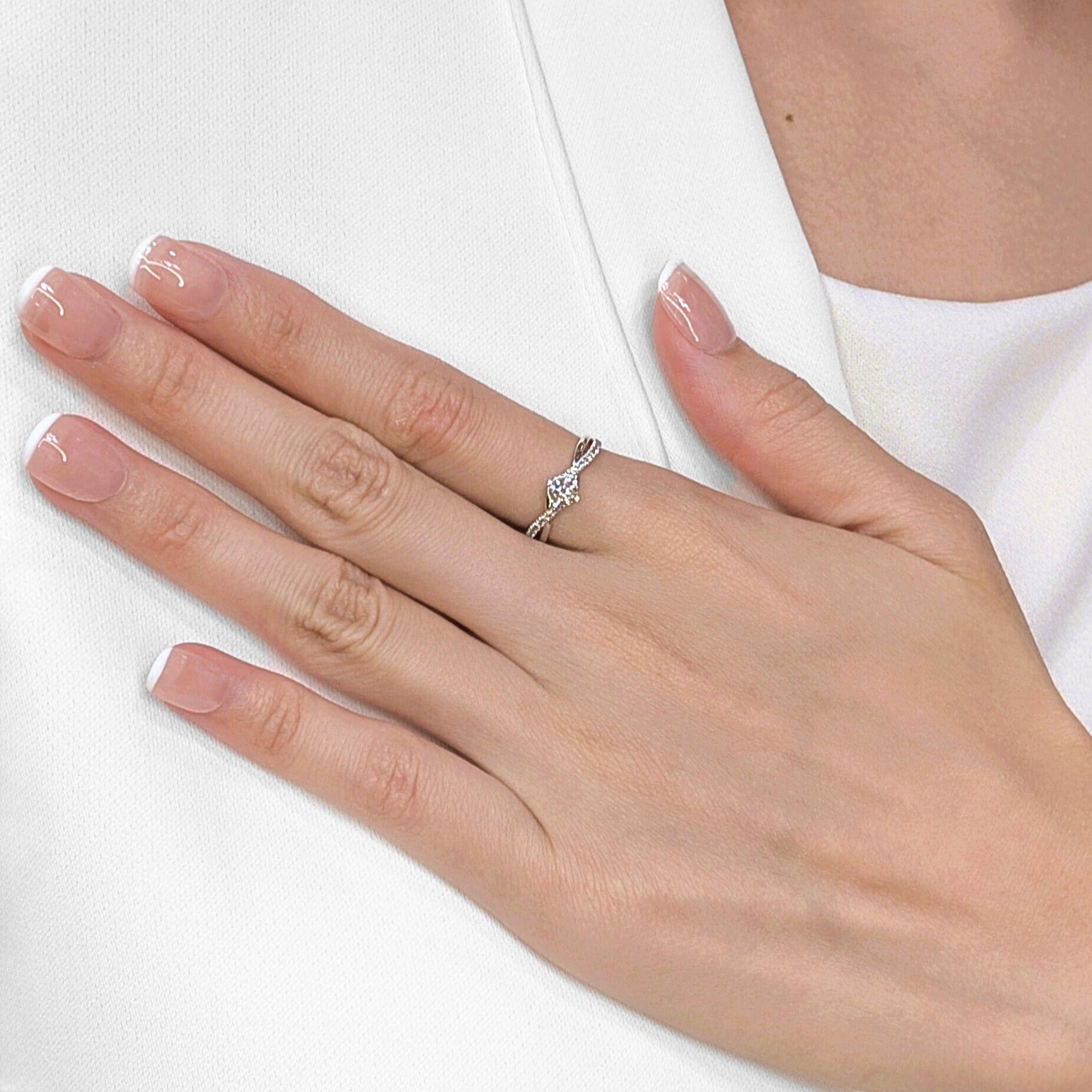 Adorn your hand with the captivating elegance of this graceful ring, featuring a unique twisted shank design meticulously crafted in radiant 18K white gold. At its heart shines a brilliant 0.37ct natural round brilliant diamond, with a charming K/L