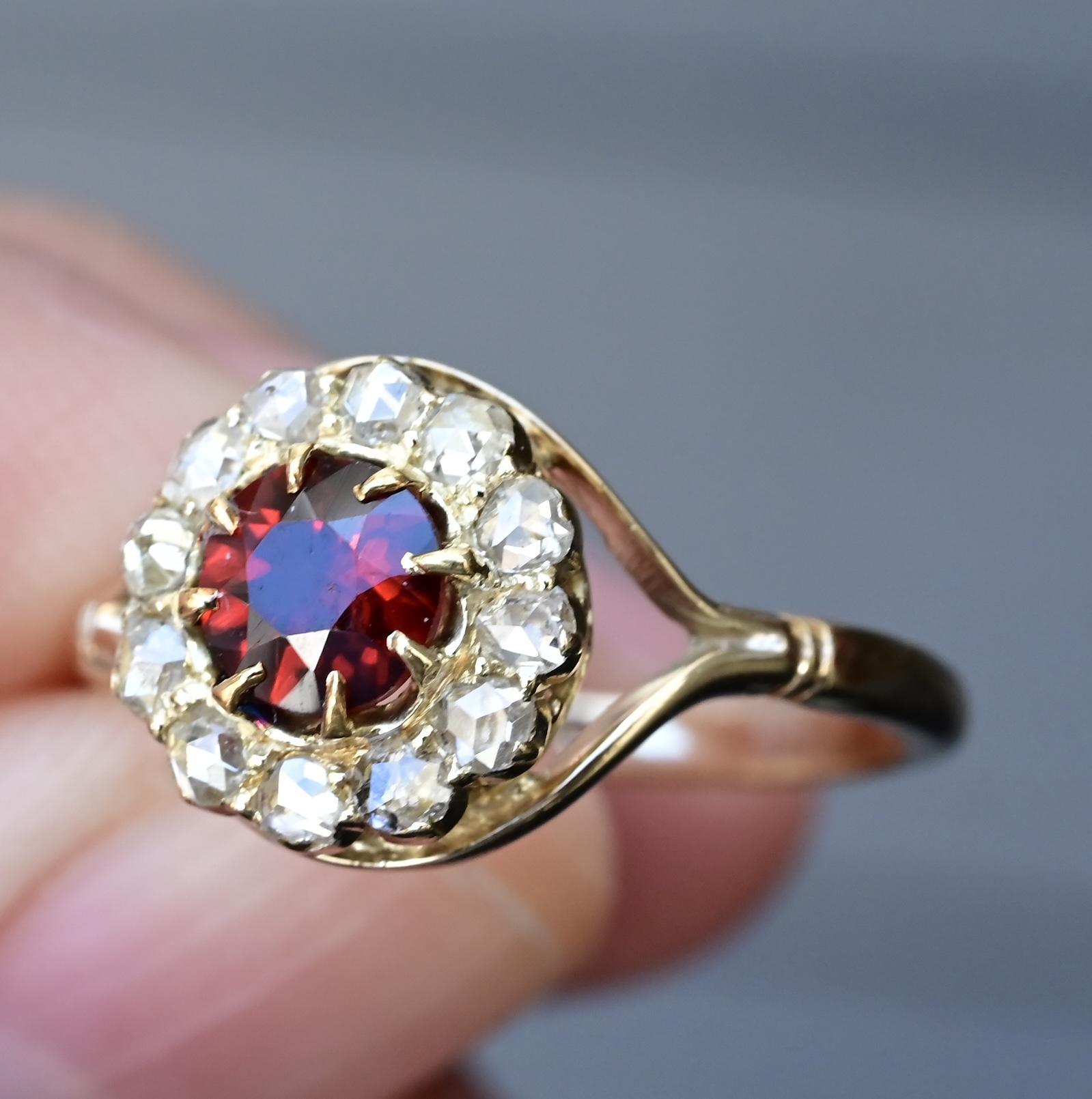 This exquisite Victorian-era ring is crafted in solid 14K yellow gold and features a stunning .66-carat deep red garnet as its centerpiece. The garnet is beautifully framed by a halo of antique diamonds totaling .30 carats, likely old mine or
