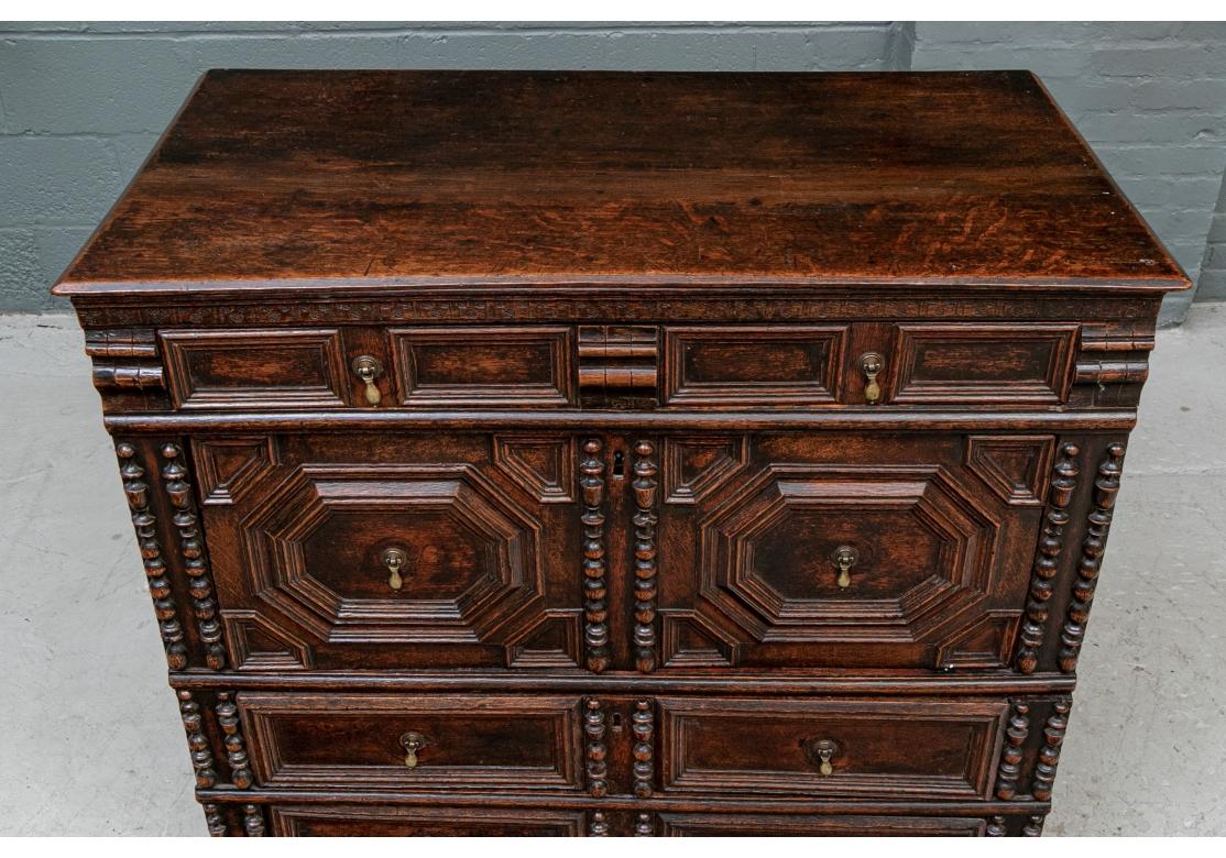 In a dark stain made in two parts, the top with a carved frieze over a slim drawer with carved moldings. A wide drawer below with carved octagonal and bead-and-reel moldings. The lower case with two carved long drawers with matching side and center