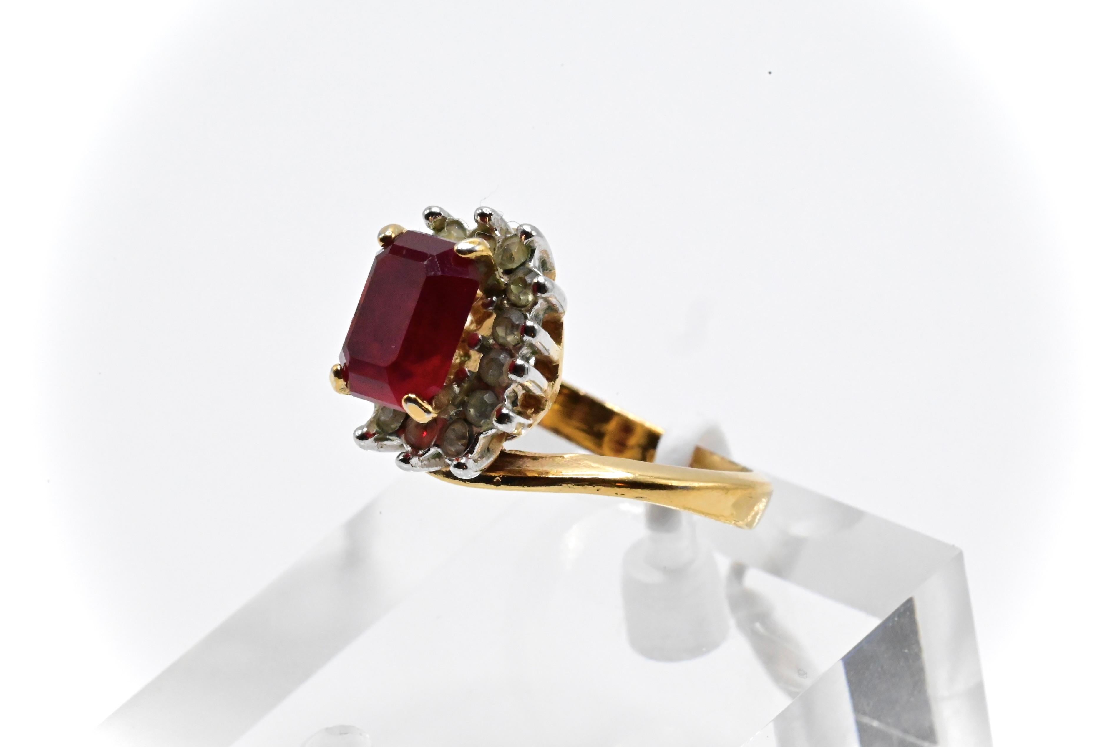 This is an elegant 18k yellow gold & emerald cut garnet ring with a beautiful deep red color. The ring has diamonds placed around the gemstone, and It’s in good condition with wear due to age and use. It’s a size 4 1/2, and weighs 3 grams. If you