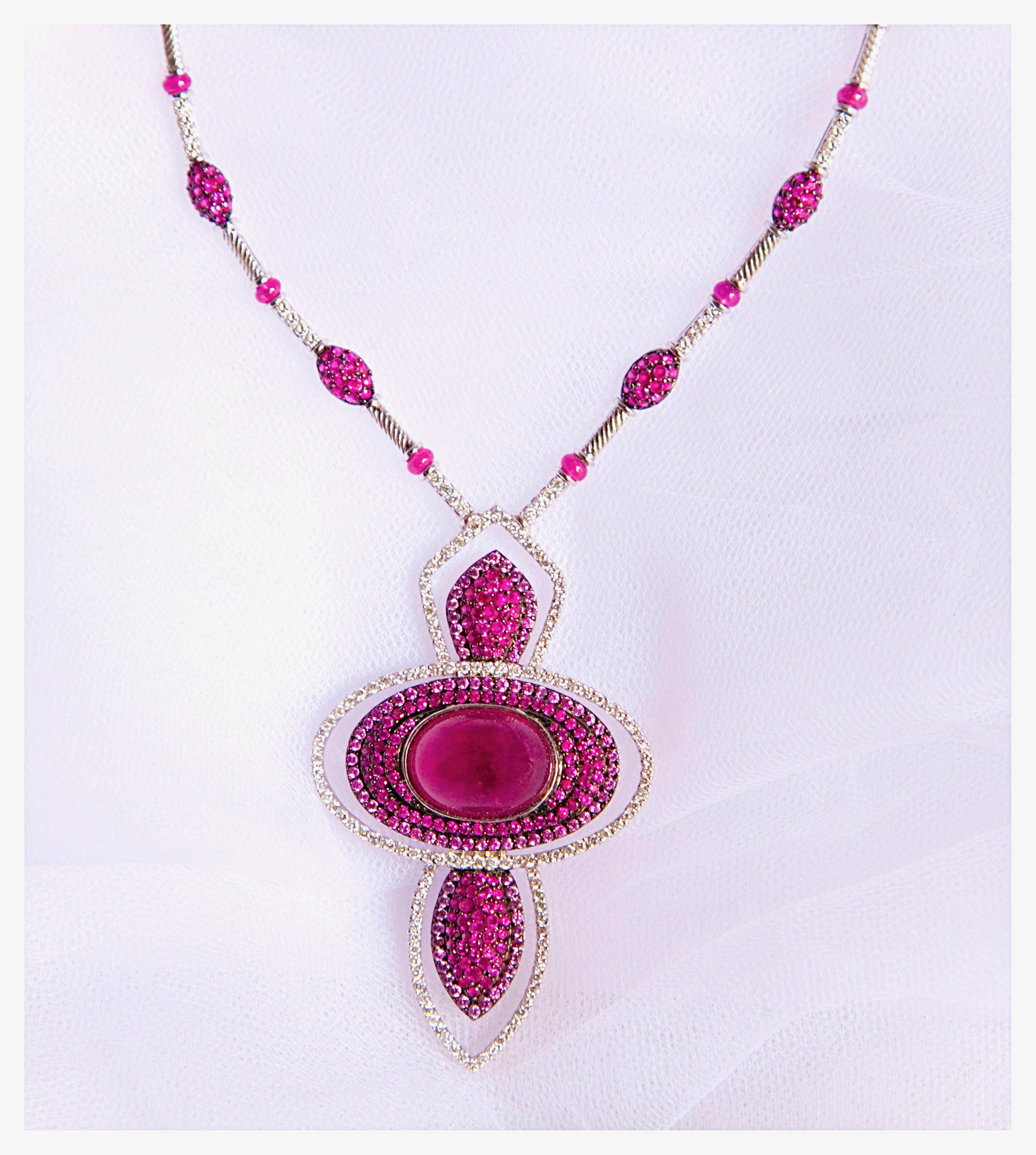 Sensational 18 Karat white gold necklace showcasing a captivating palette of pink and red with the central 22,95 carat natural pink tourmaline cabochon,  enhanced by  21,07 carat rubies and pink sapphires  exquisitely curated and 3,55 carat natural