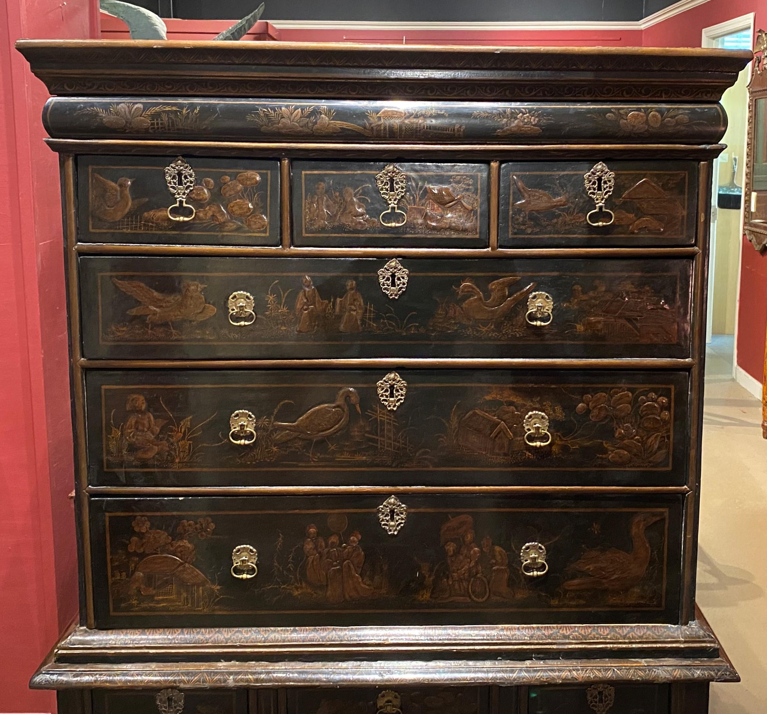 An exceptional English Chinoiserie or Japanned lacquered two part oak highboy with a molded cornice surmounting an upper case with hidden document drawer over three small fitted drawers over three graduated long drawers, each featuring relief carved