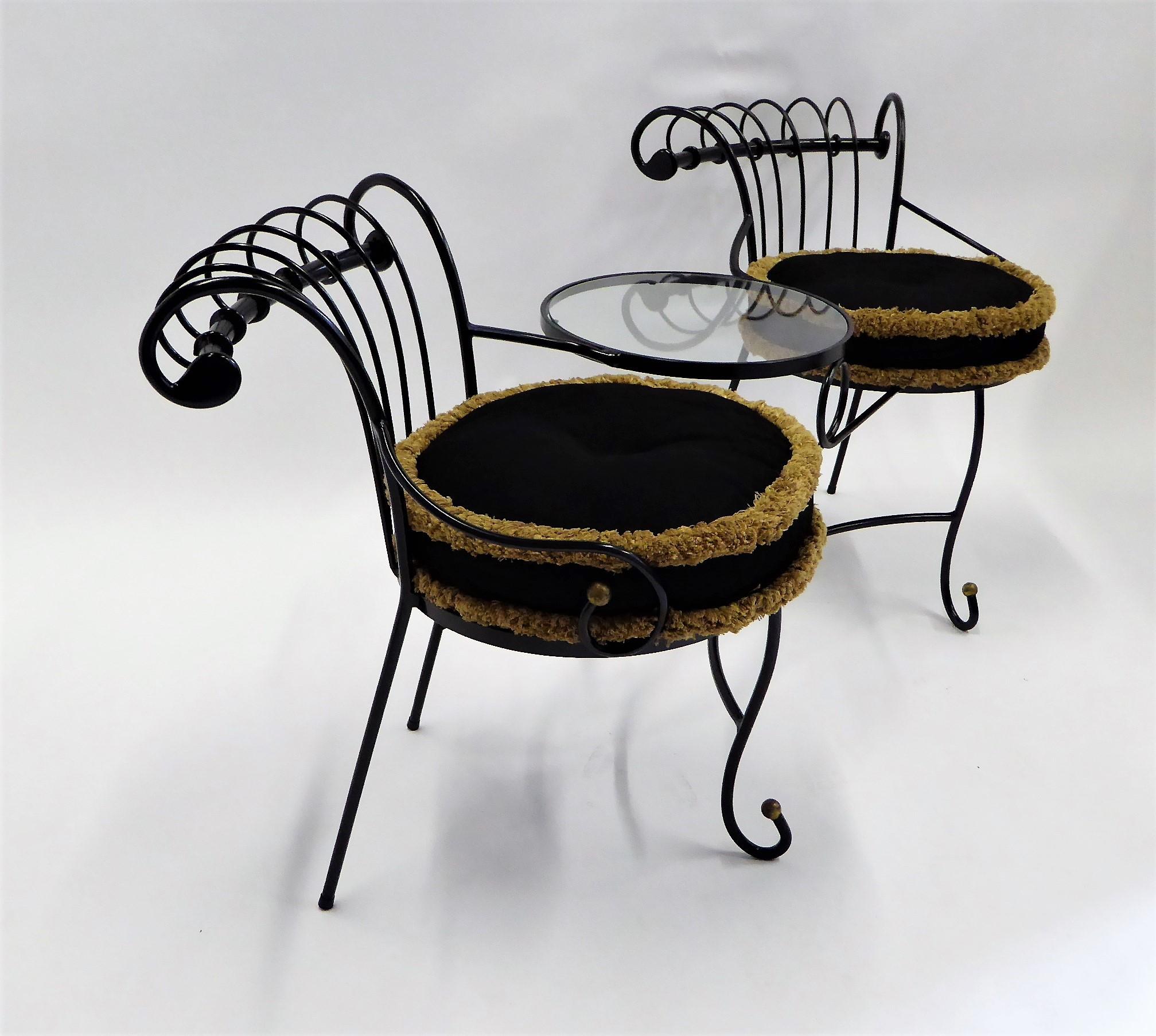 This exceptional wrought iron Tete a Tete or settee is either French or Italian and is heavily influenced by the designs of Maurizio Tempestini for Salterini. Having a small circular glass table between the seats and a curved design on the seatbacks