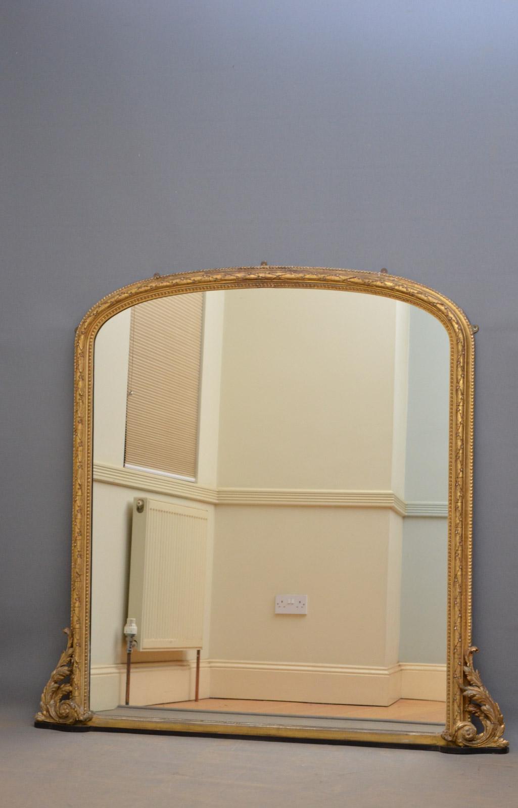 K0349 Exceptional early 19th century giltwood wall mirror, having original mirror plate with foxing in finely carved frame with scrolls to base. This antique mirror retains its original finish with wear consistent with age and use, original mirror