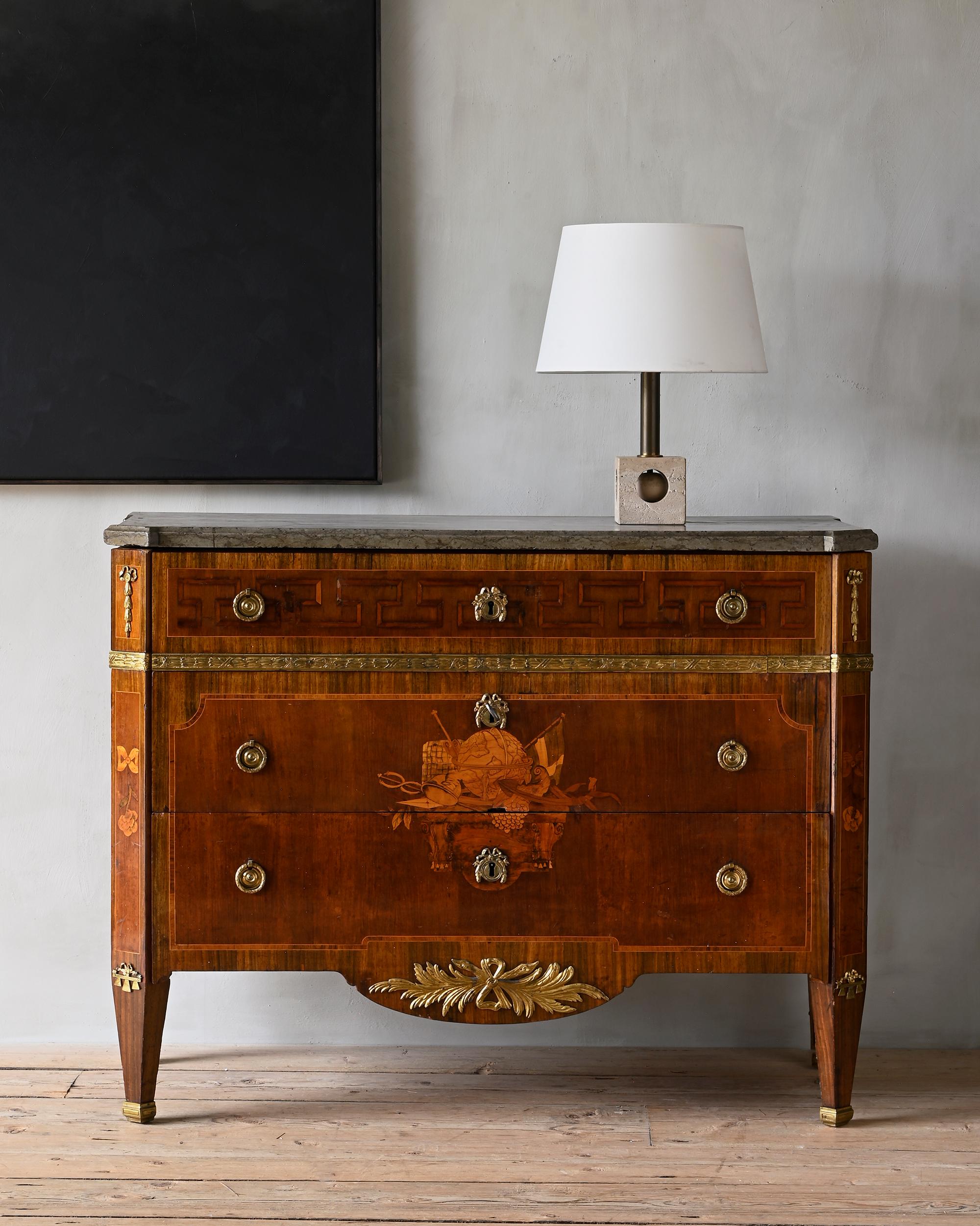 Exceptional early 19th century Gustavian chest of drawers veneered with amaranth, birch, jacaranda and maple. Limestone top, gilt brass fittings, à la greque upper case and sides, front with marquetry symbolising seafaring and commerce with emblems