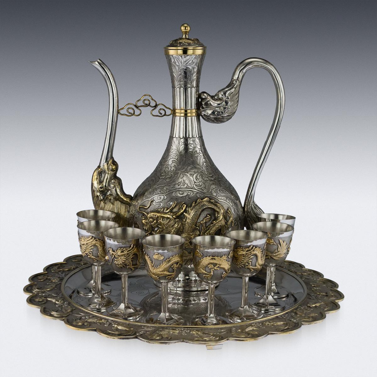 Exceptional mid-20th century Chinese solid silver-gilt sake drinking set, comprising of a large ewer, eight goblets and a large tray. Each piece is part-gilt and extremely decorative, ewer chased with scrolling foliage, flying dragons and mounted