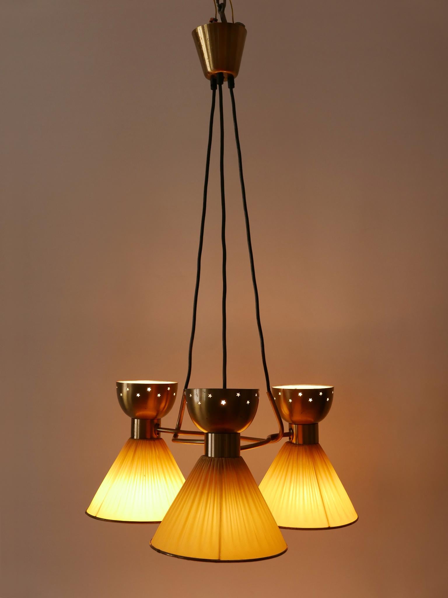 Rarissime, très décorative et élégante lampe suspendue ou lustre à 6 flammes du Mid-Century Modern avec des abat-jour en diabolo. Conçue et fabriquée en Suède, dans les années 1950.

Réalisée en tôle / tube de laiton partiellement perforé et en