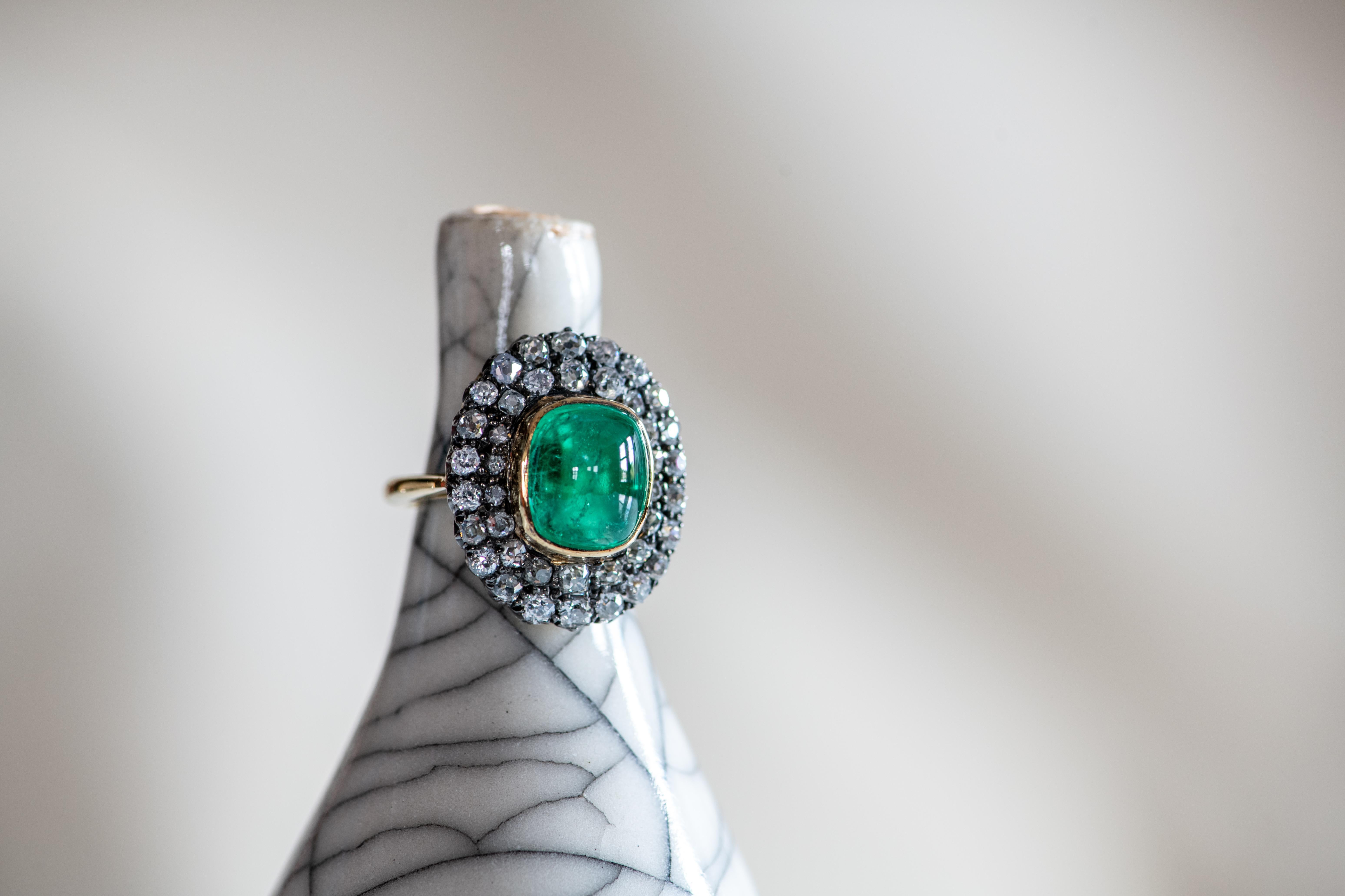 The large cabochon emerald at the centre of this vintage-style ring is bold and bright, its vivid green colour accentuated by a double-layered surround of round brilliant white diamonds. Hand-crafted in the Haruni workshop, this is a dazzling ring